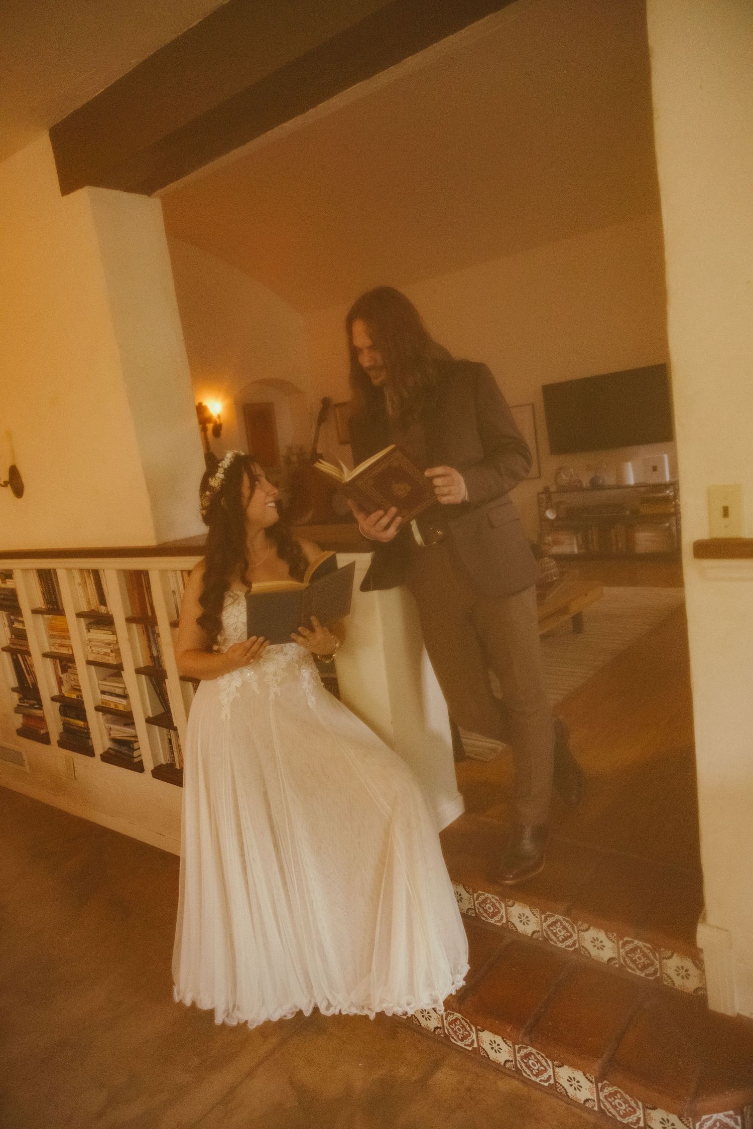 Bride in white gown and groom in dark suit share vows indoors, officiant holding book during intimate wedding ceremony.
