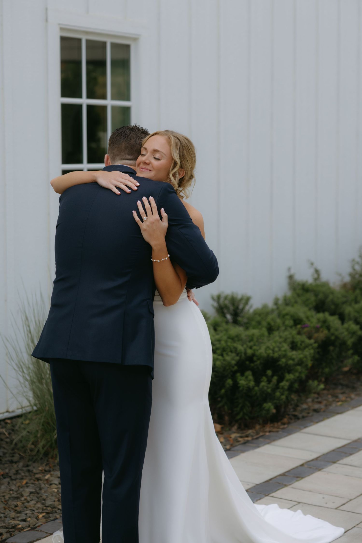 A series of emotional first look wedding photos showing tender embraces between a bride in white and someone in a navy suit.