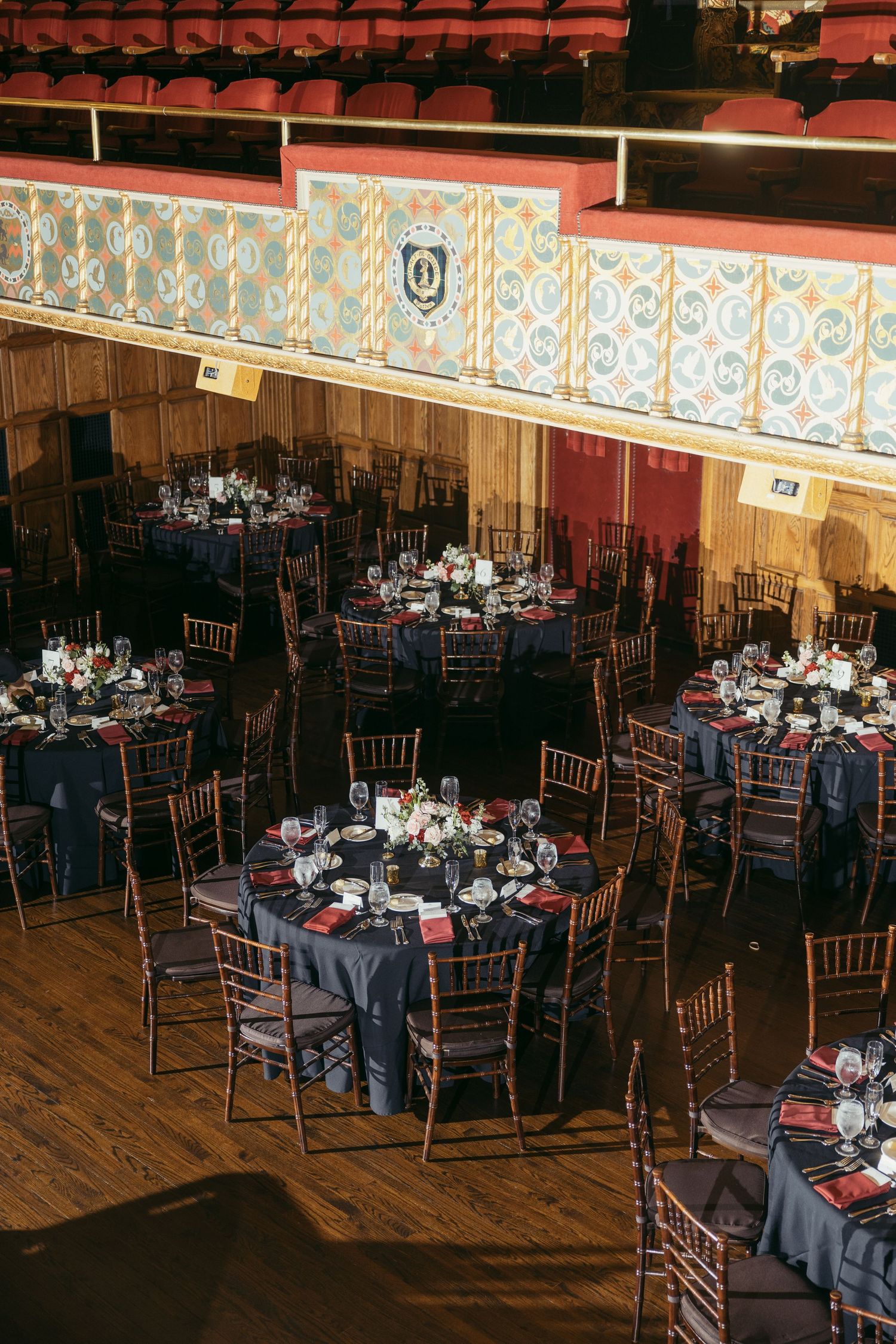 Elegant wedding reception in a historic venue with navy blue tablecloths, chiavari chairs, and floral centerpieces.