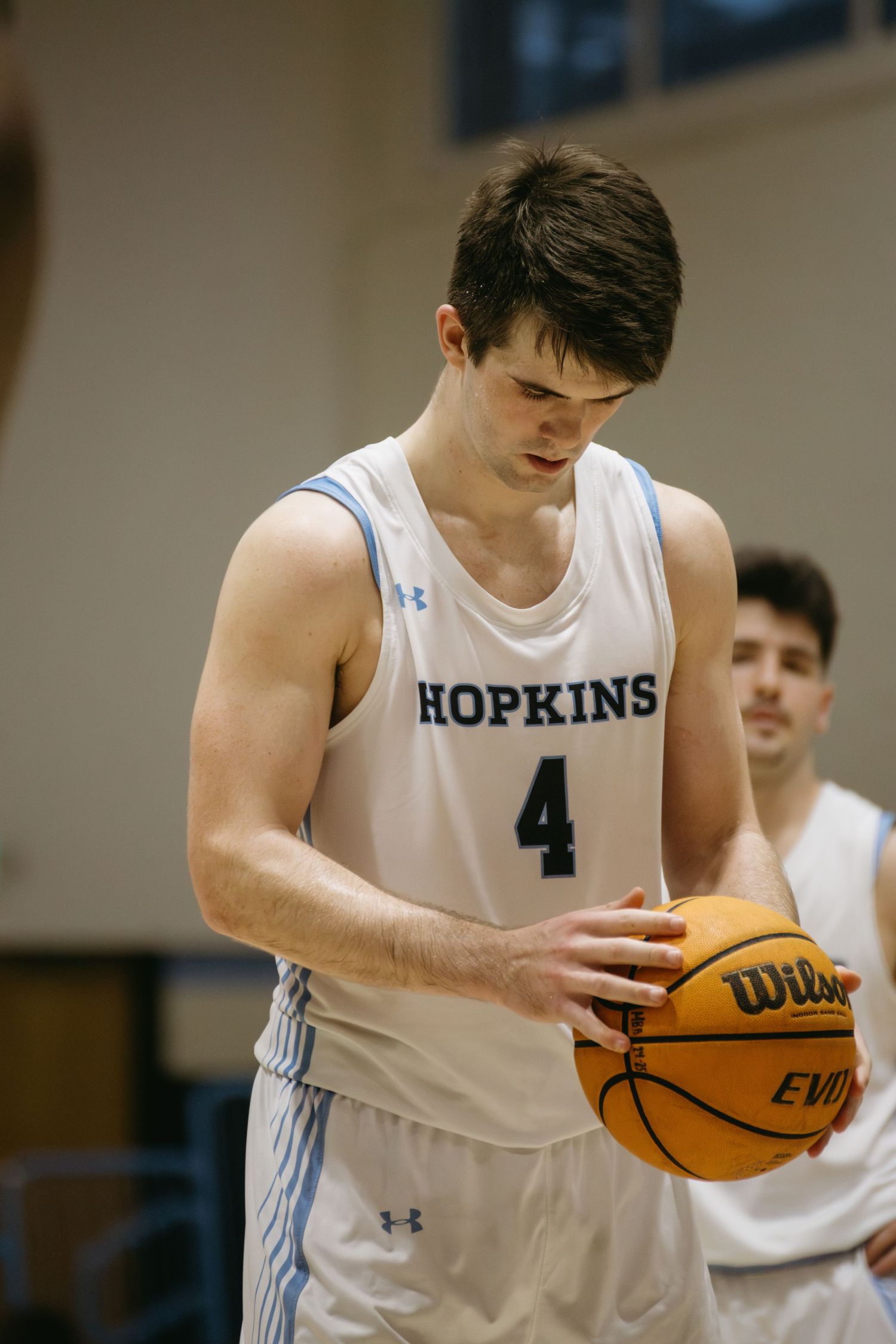 Basketball player in Hopkins jersey number 4 concentrating on ball during game.