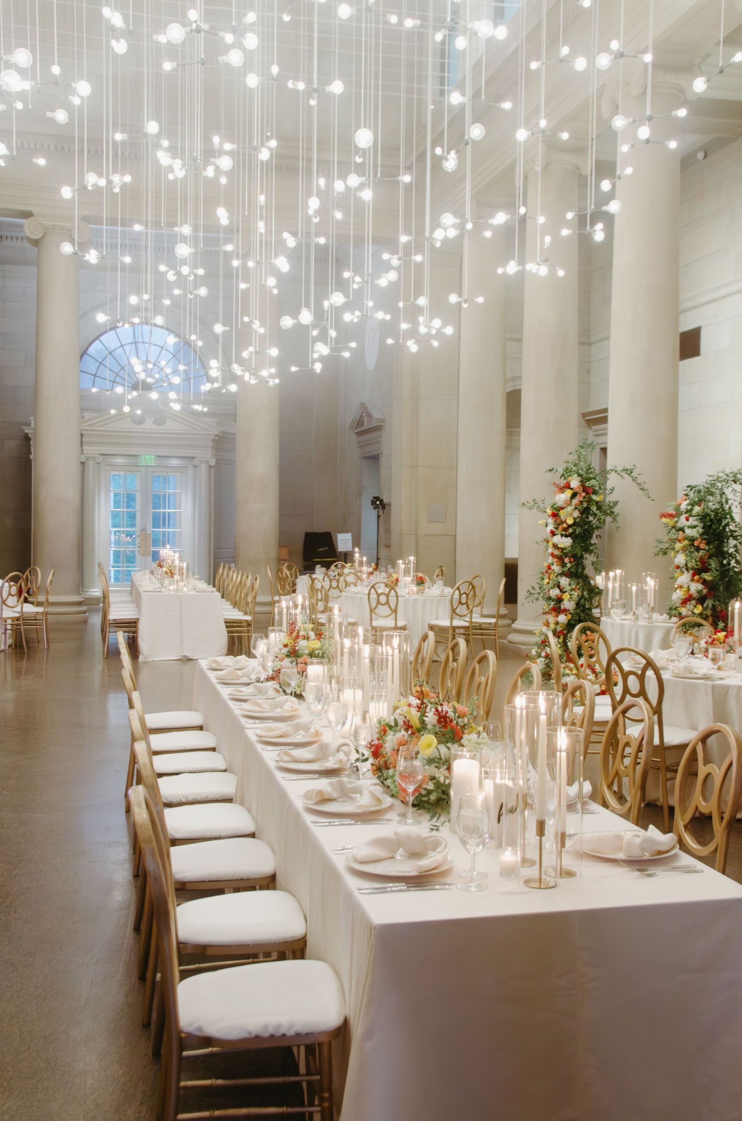 Elegant wedding reception venue with hanging lights and long table settings.