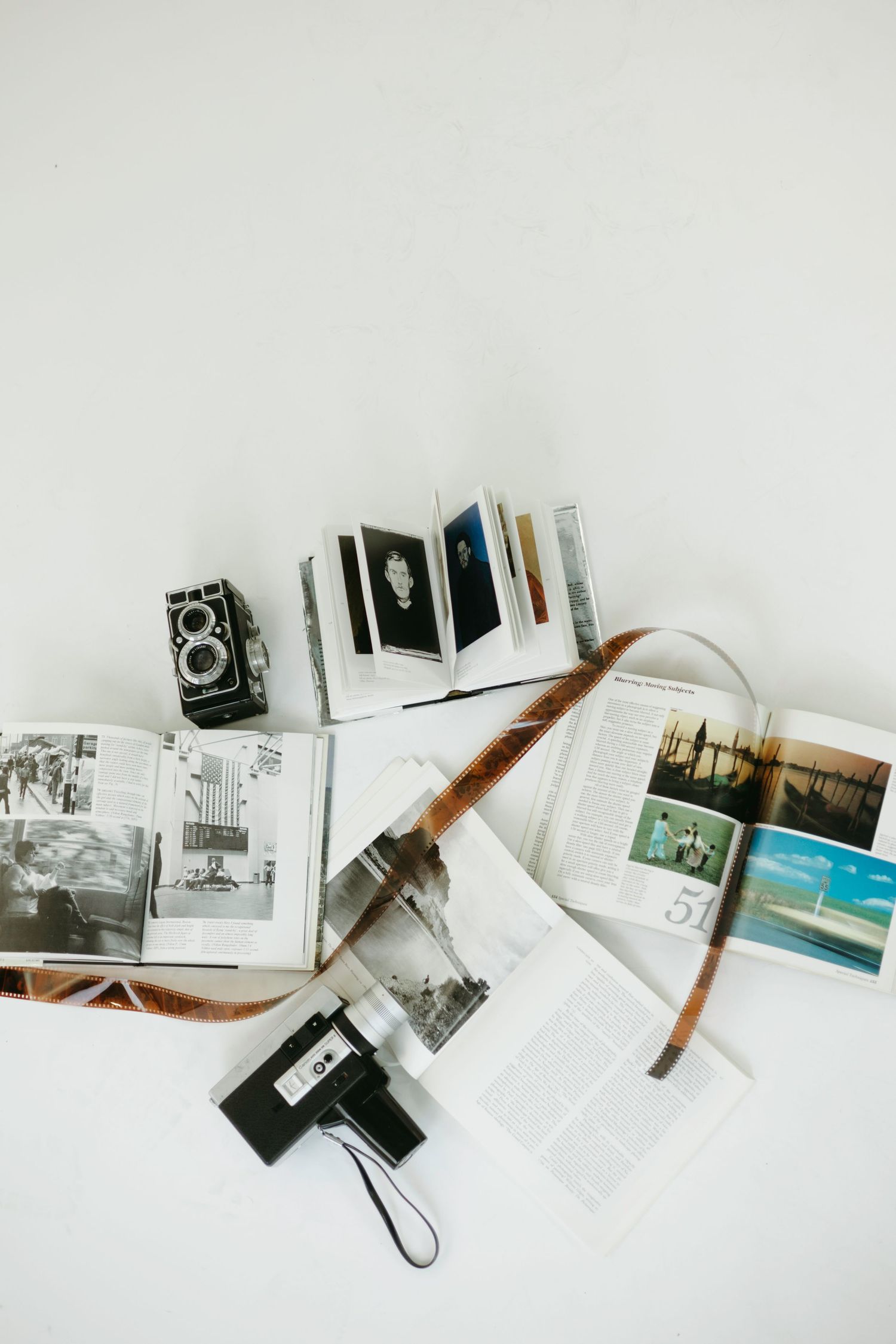 Vintage camera and photo albums with black and white photographs spread on white surface.