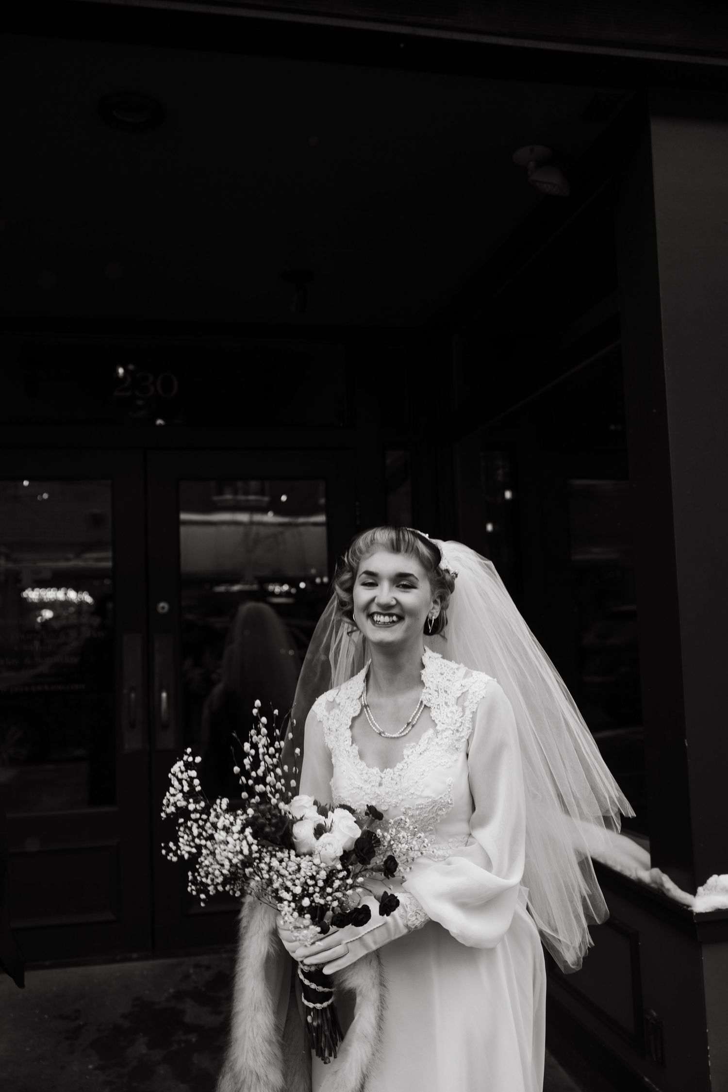 A bride in a white lace wedding dress and veil holds a bouquet while smiling during a photo sequence.