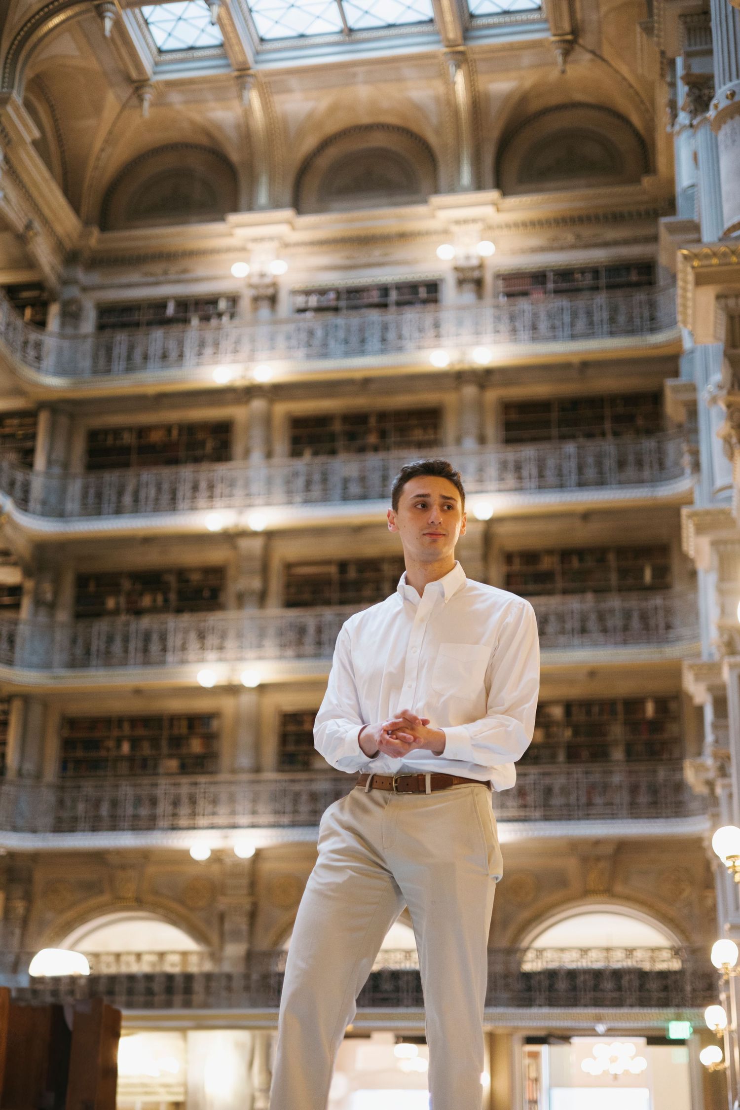 Historic library interior featuring ornate balconies, skylights and grand architecture in warm golden tones.