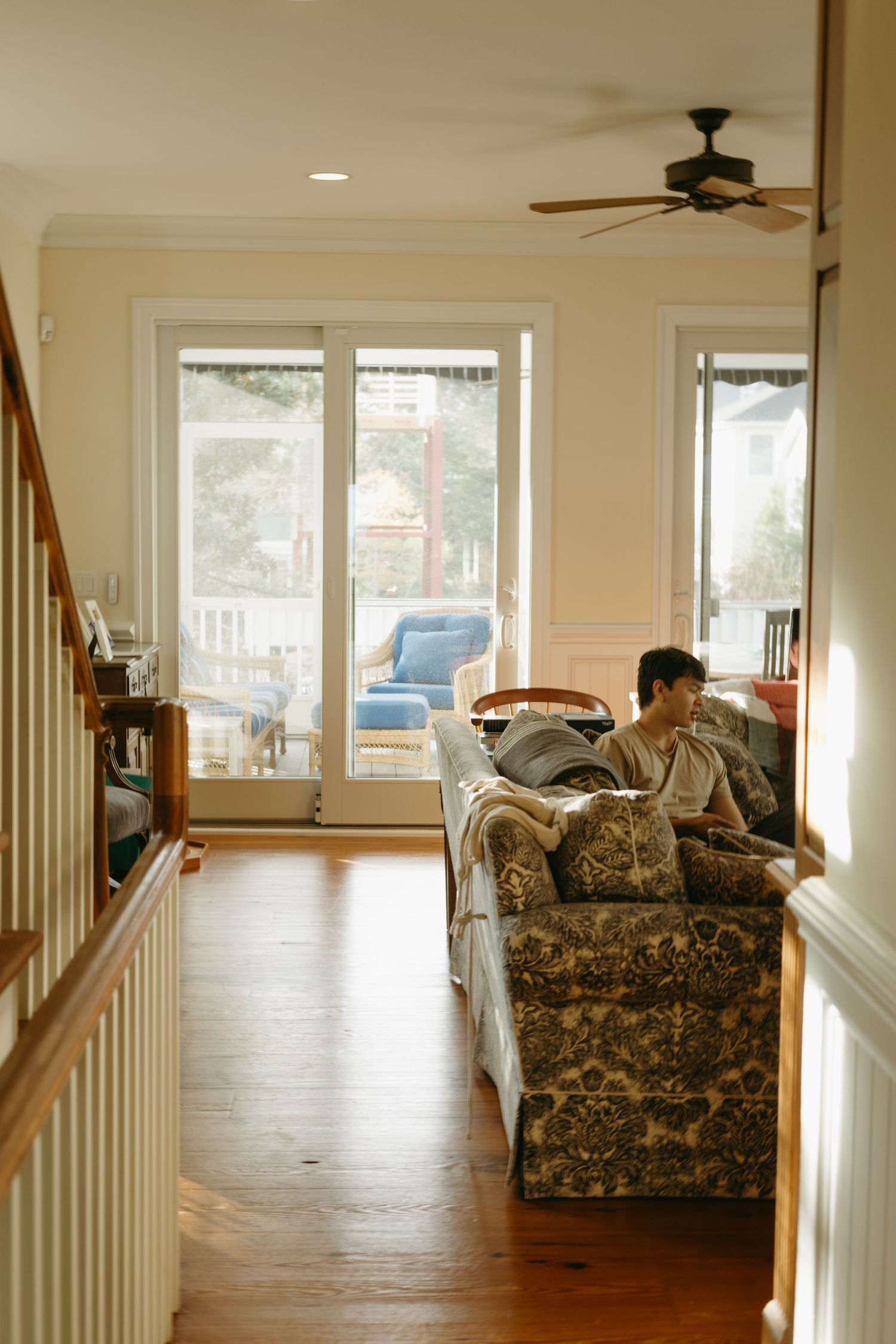 A cozy living room interior with hardwood floors, French doors leading to a porch, and a floral patterned armchair.