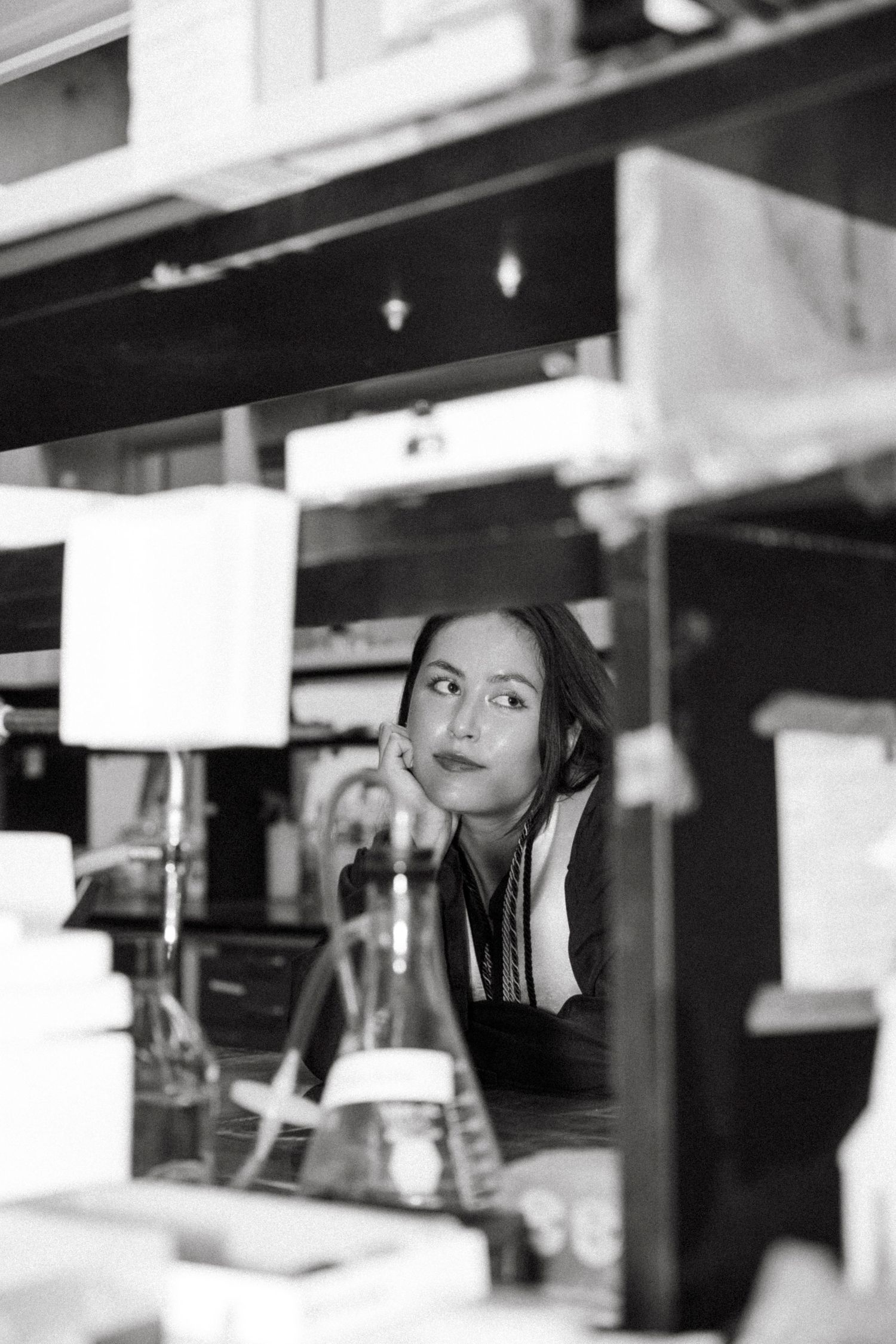 Black and white photo showing person thoughtfully looking up while working behind a counter in what appears to be a cafe.