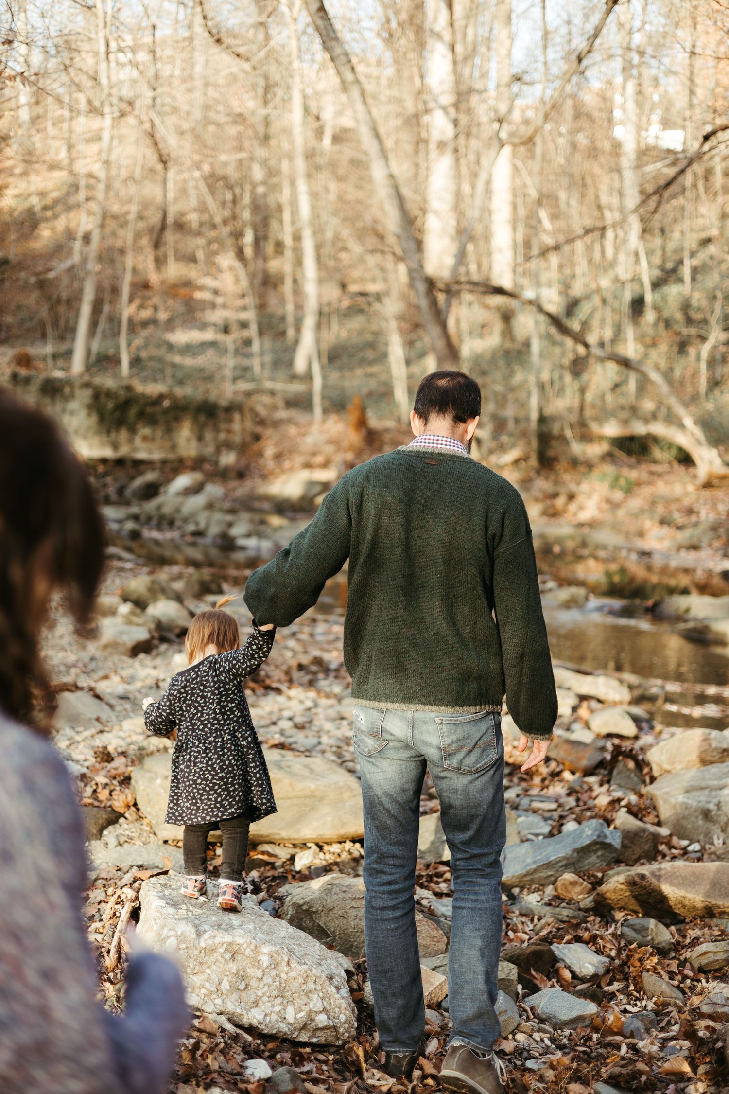 Walking together along a rocky creek bed through autumn woods.