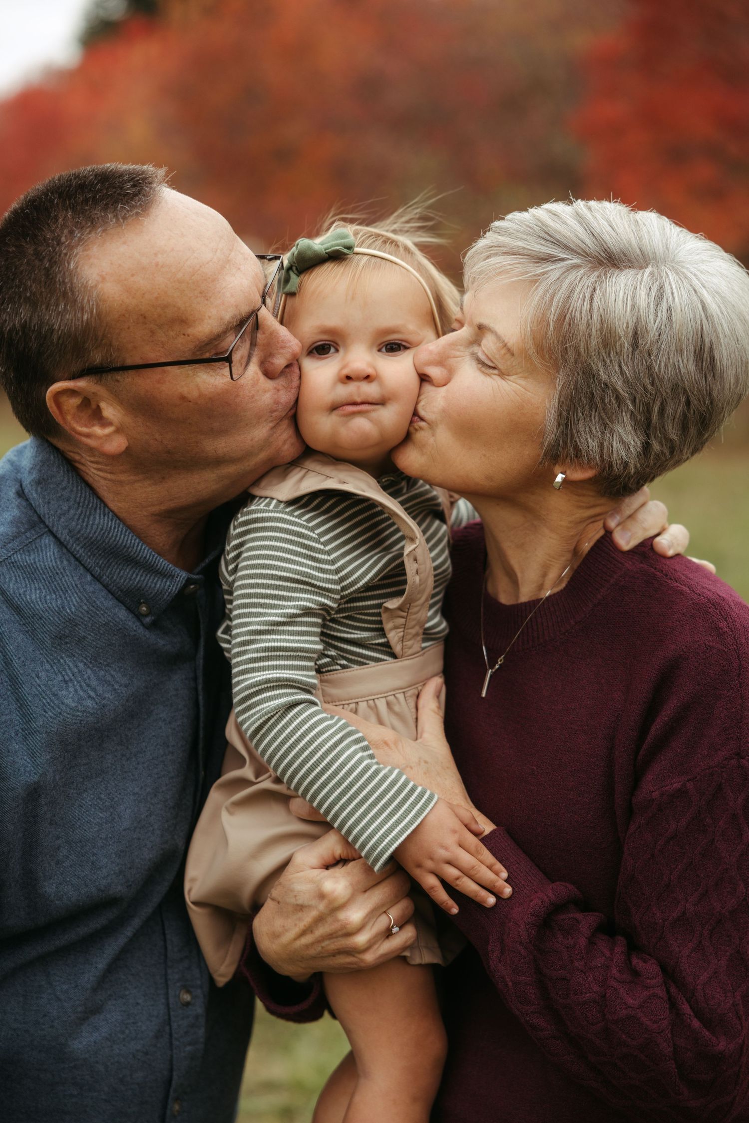 A sweet moment between three generations sharing kisses and embraces outdoors during autumn.