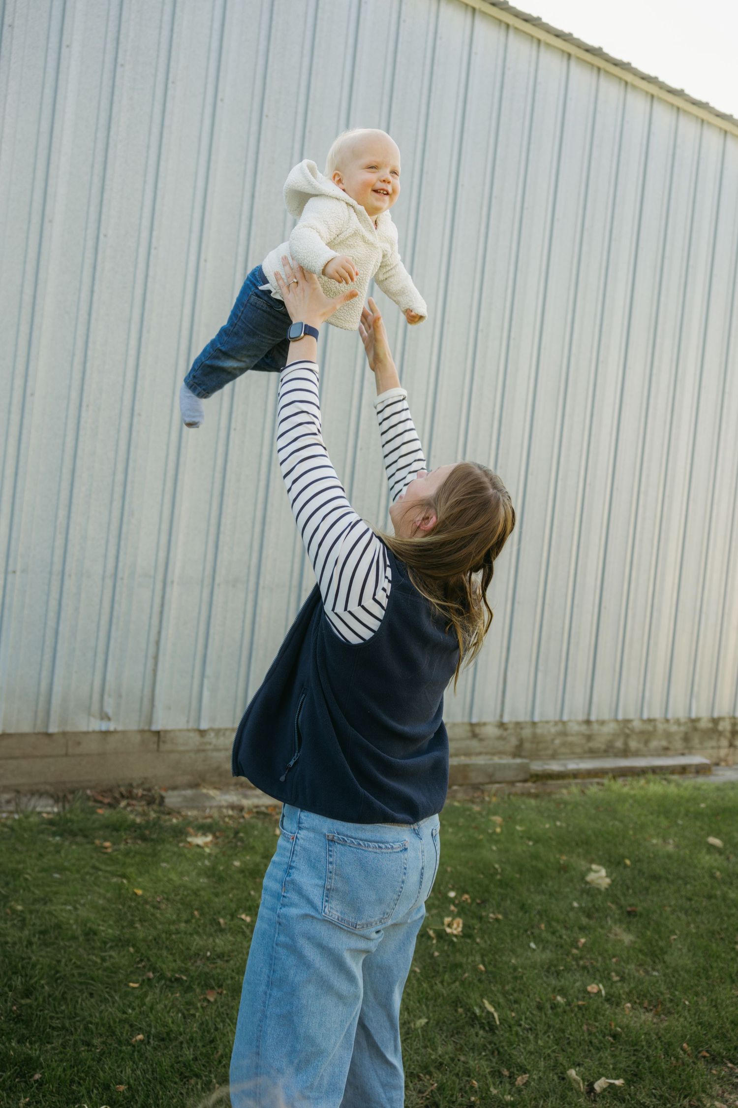 A series of four photos showing someone playfully lifting a baby up in the air against a metal wall background.