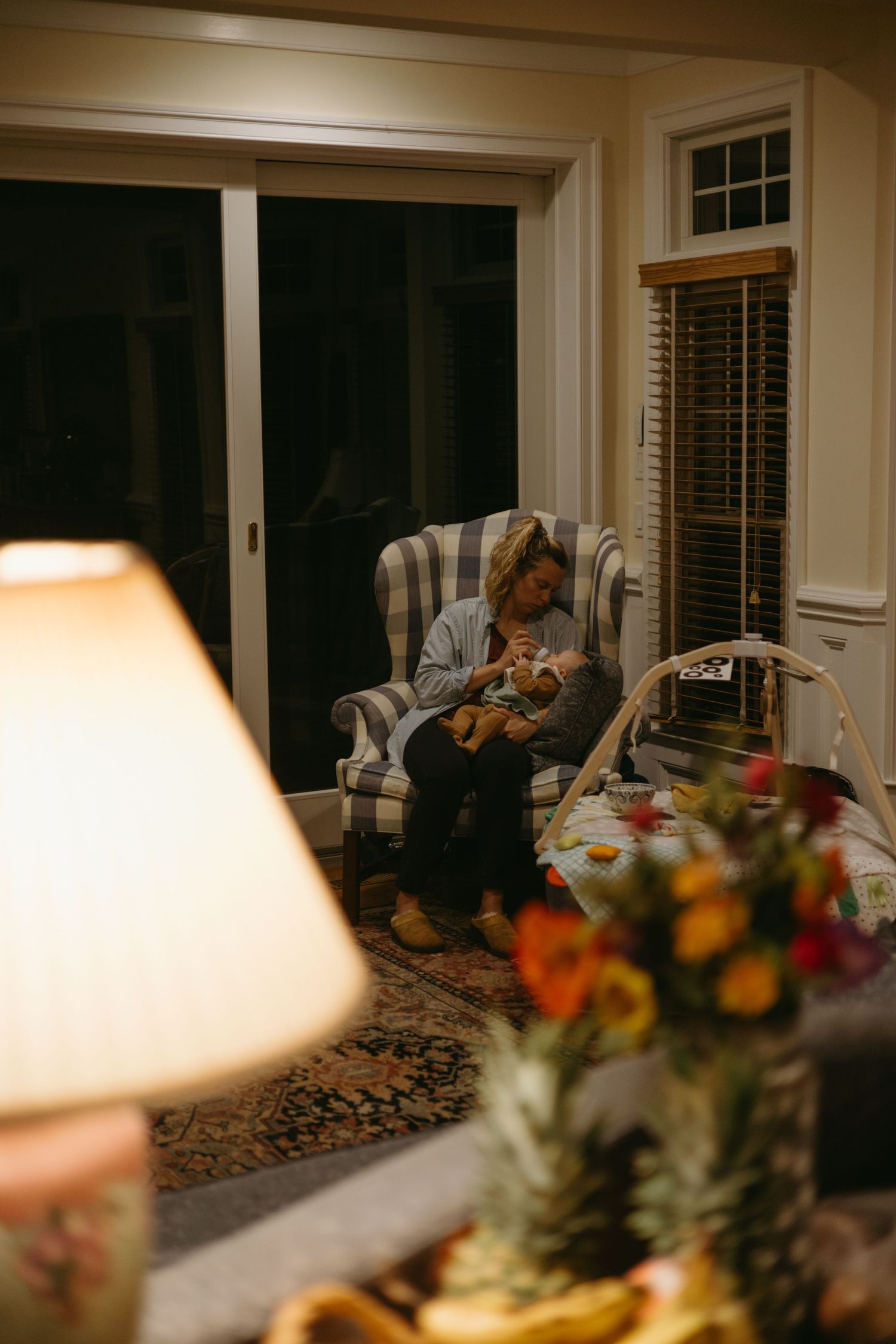 Cozy evening scene with a striped armchair, soft lamp lighting, and colorful floral arrangement in the foreground.