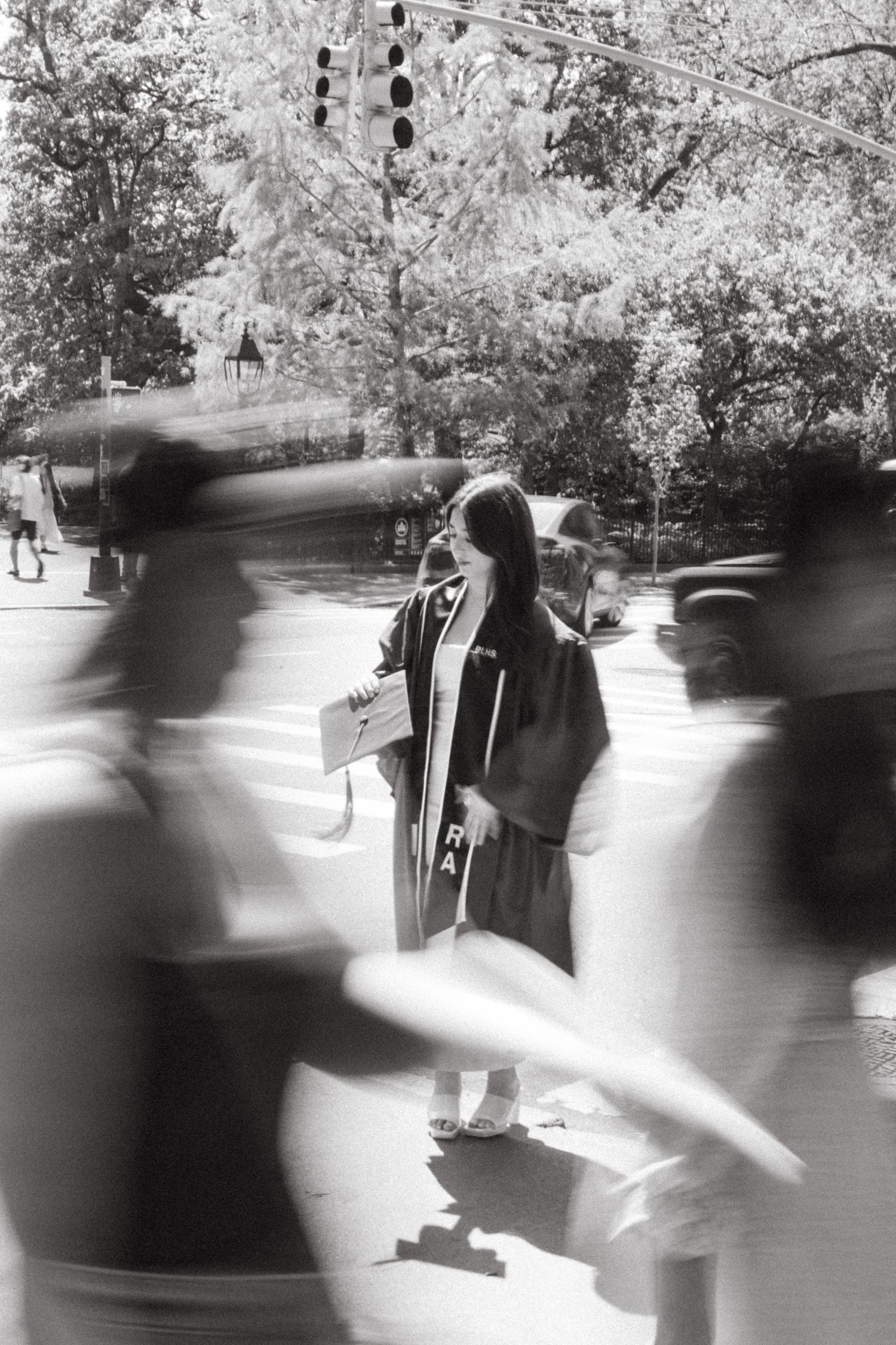 Black and white motion blur photograph of graduation ceremony with trees in background.