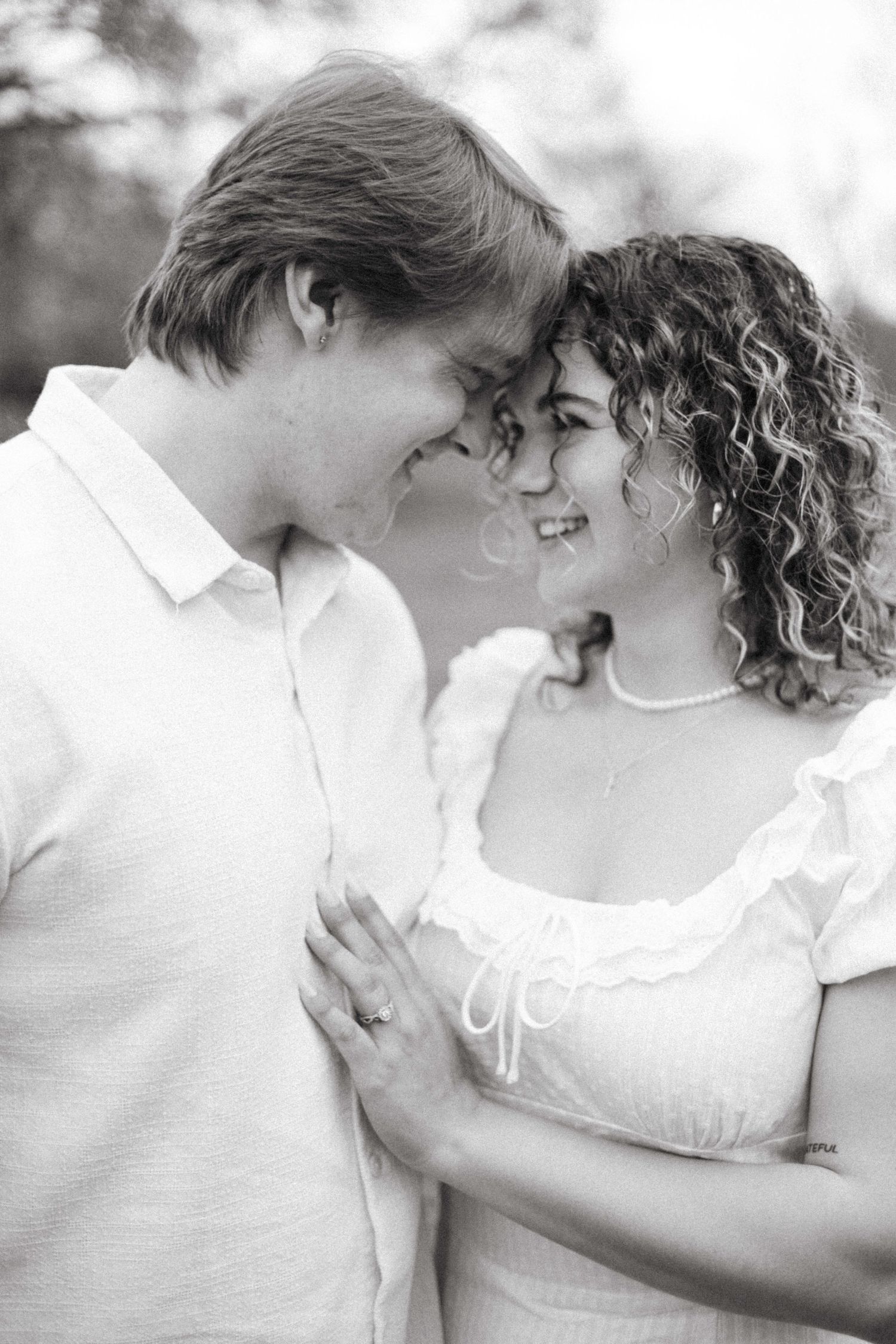 A tender romantic black and white portrait of a couple in white clothing sharing an intimate moment together.