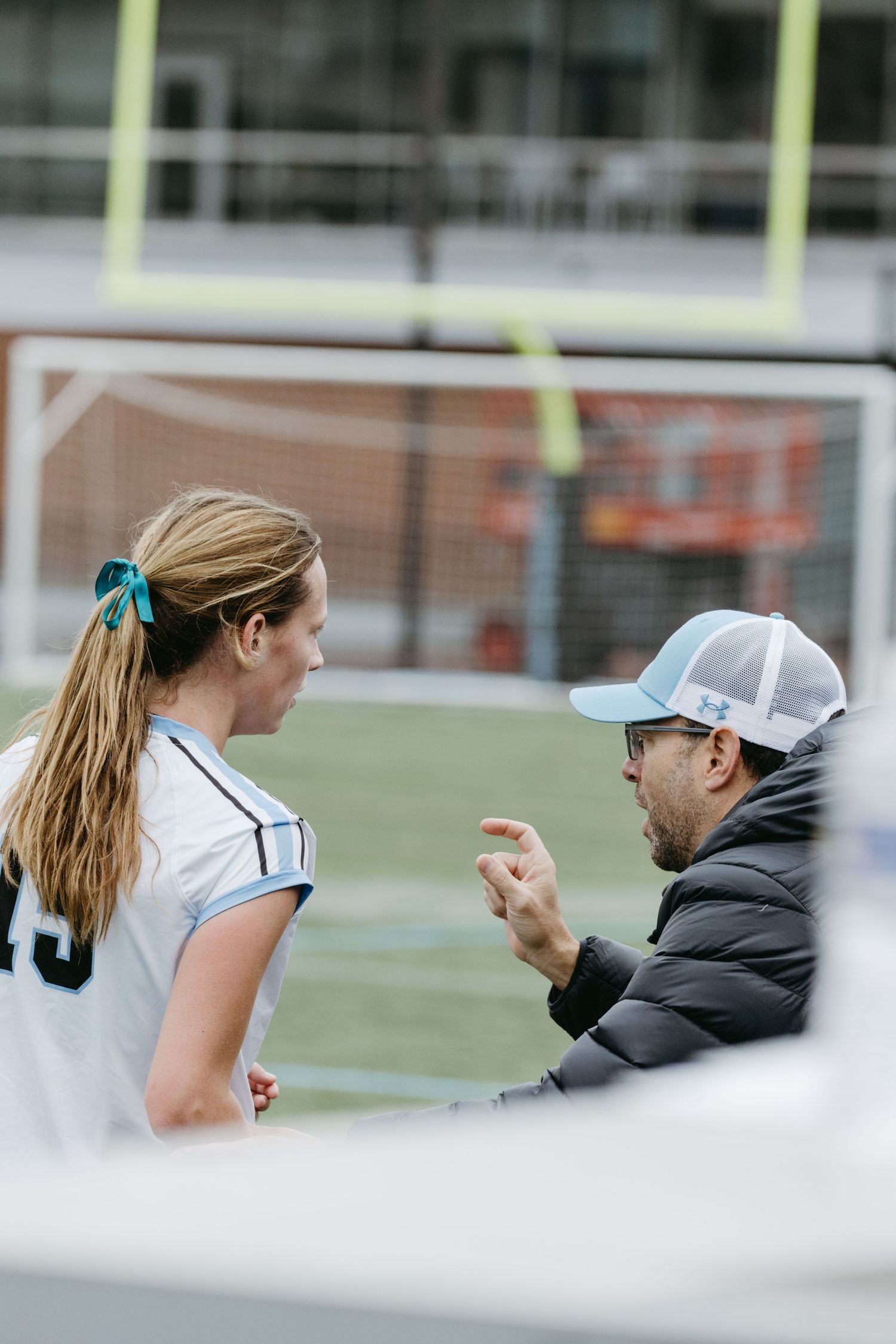 Coach and player engaged in animated discussion during soccer match.