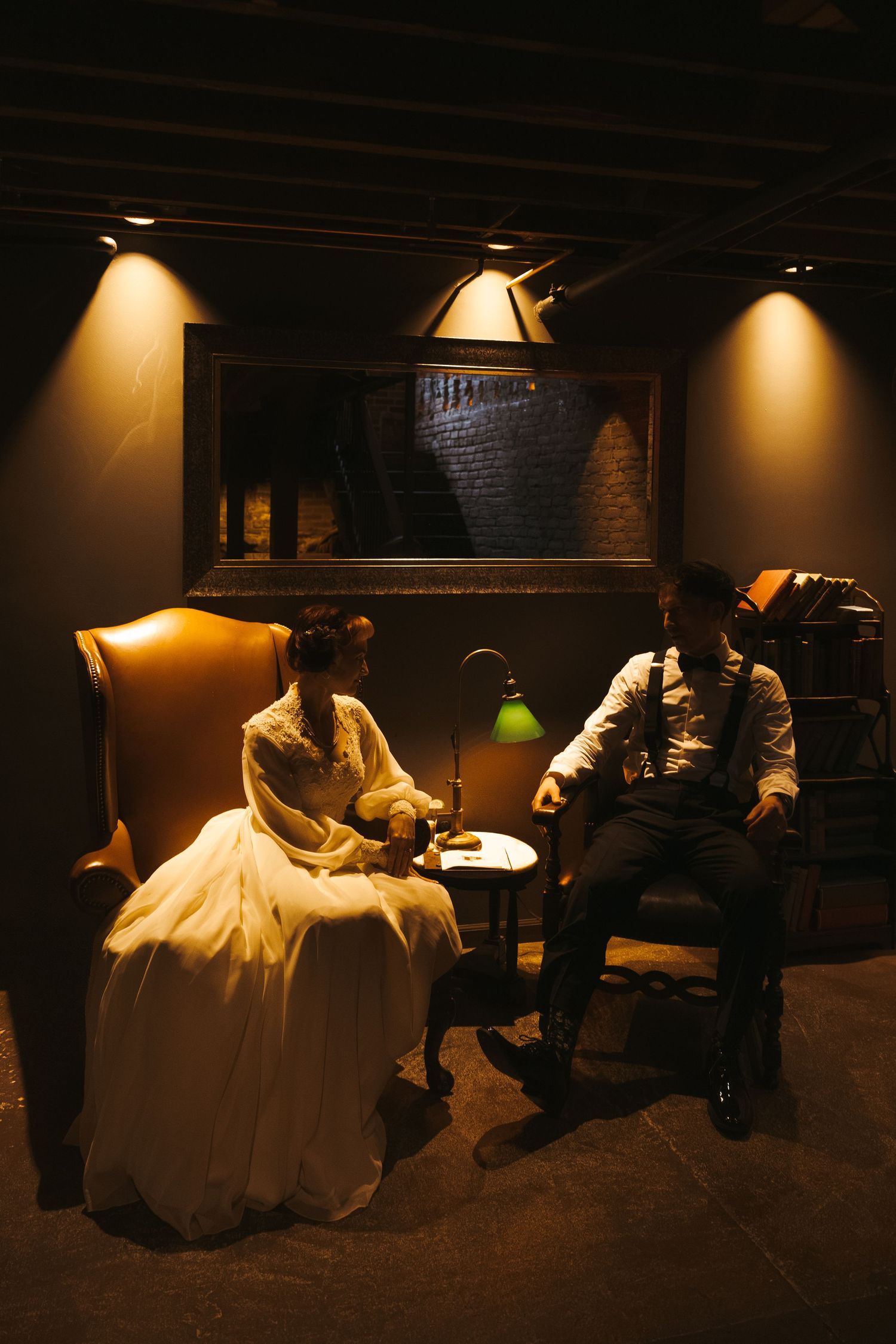 A sequence of dimly lit photos showing a wedding dress in a dark room with warm spotlights creating dramatic shadows.