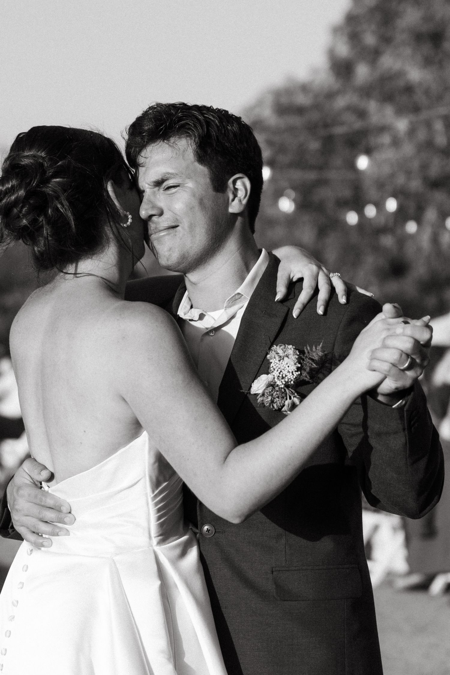 Black and white photo of bride and groom sharing their first dance outdoors at a wedding reception.