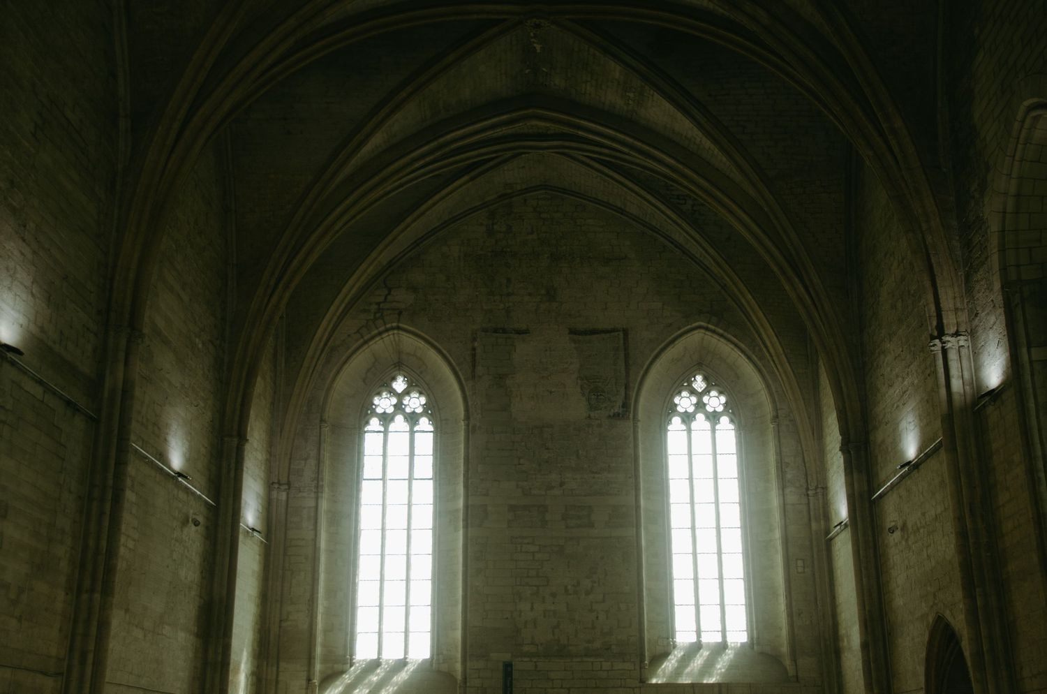 Stone vaulted cathedral ceiling with twin Gothic windows letting in bright natural light.