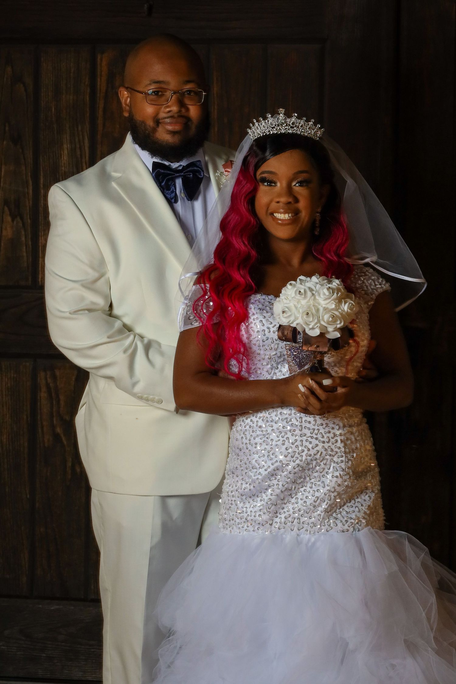 Bride in crystal gown with red hair and groom in white suit portrait.
