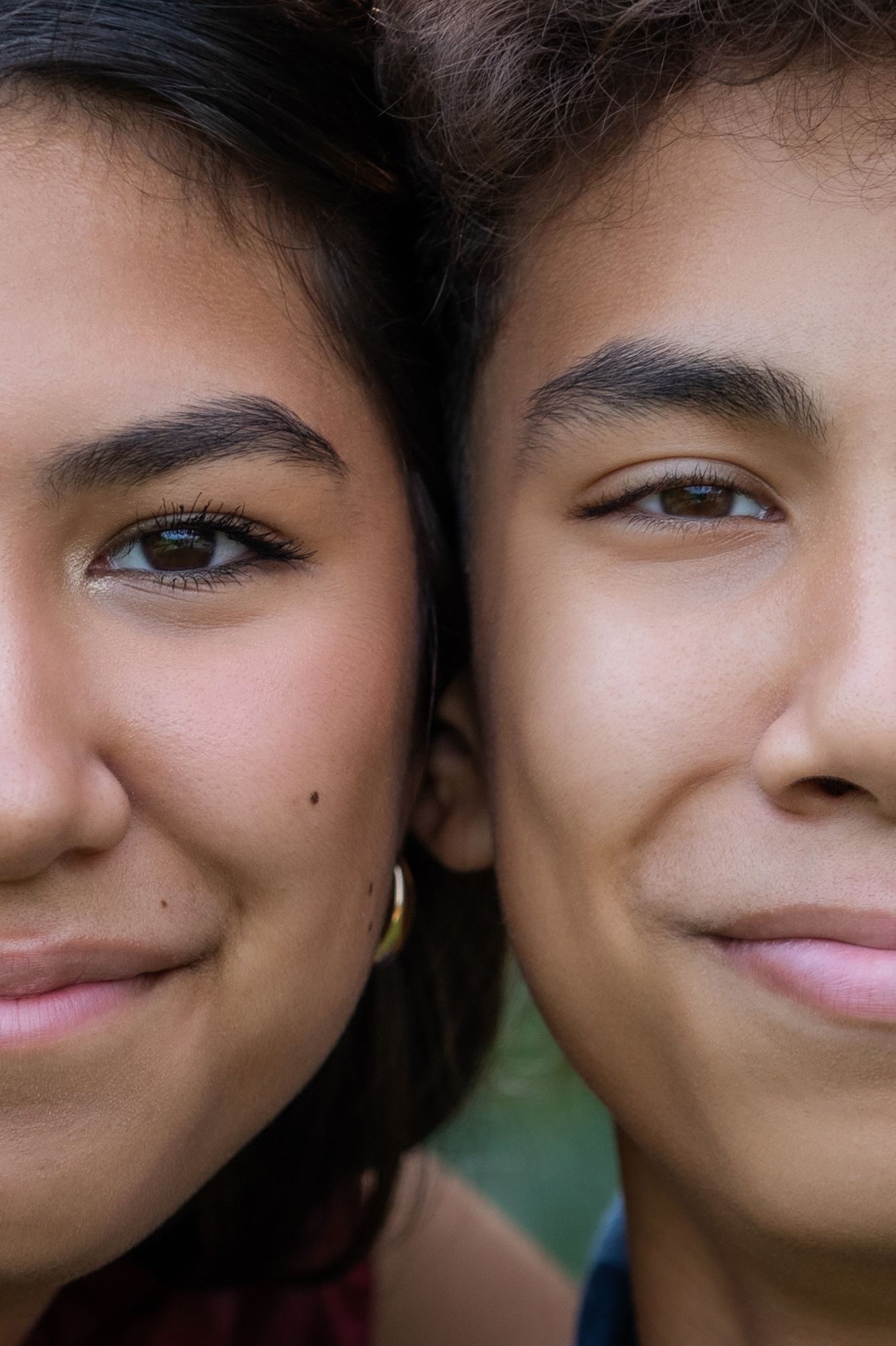 Close up portrait of two young people smiling warmly at the camera with soft lighting and blurred background.