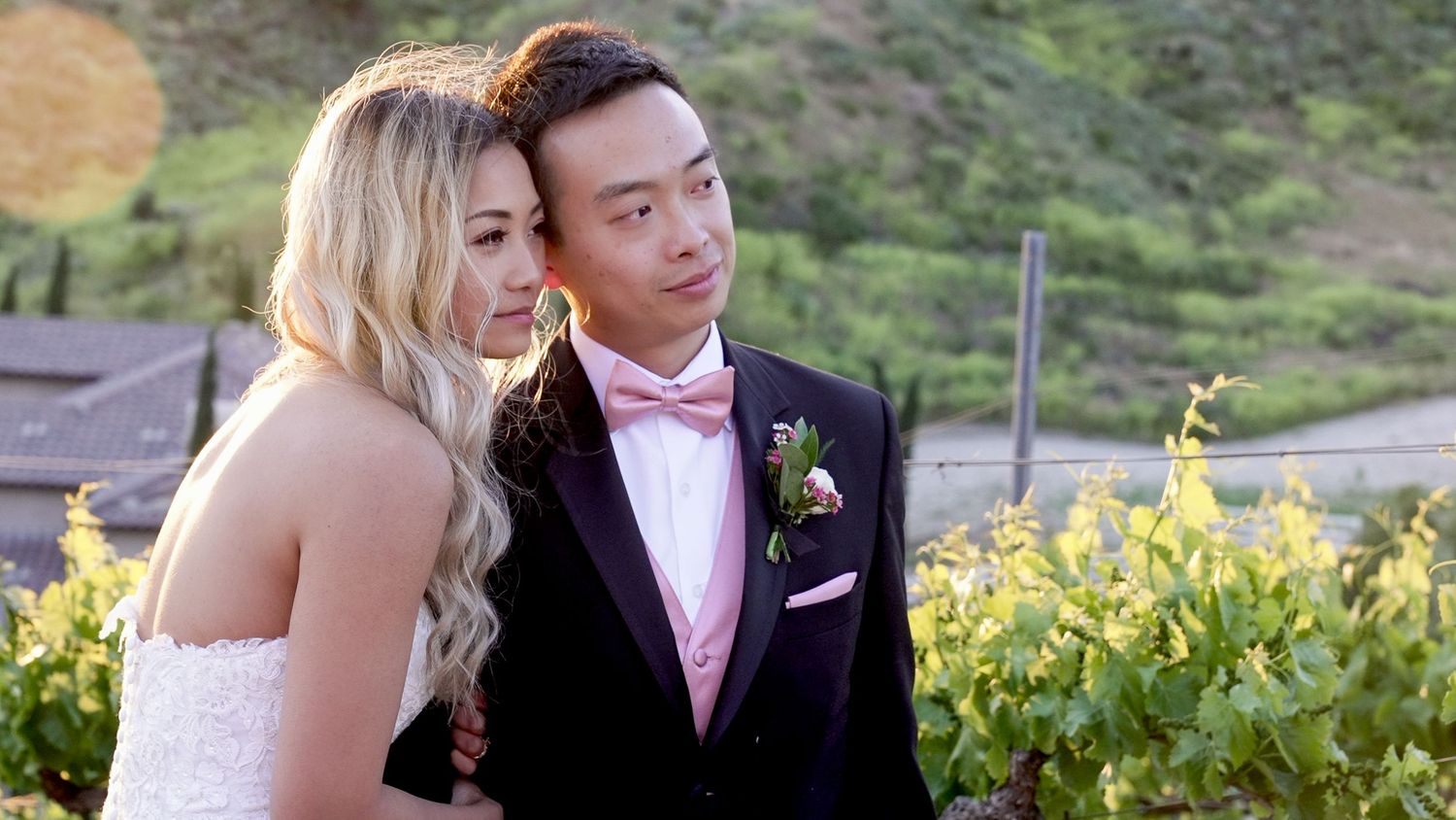 Wedding couple shares romantic moments in lush garden setting with yellow flowers in background.