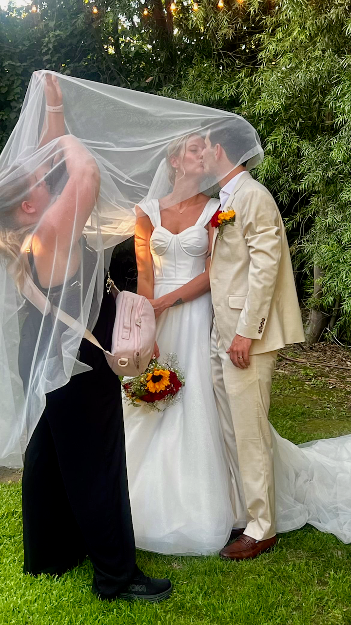 A romantic wedding sequence shows the couple sharing a kiss under the bride's veil in an outdoor garden setting.