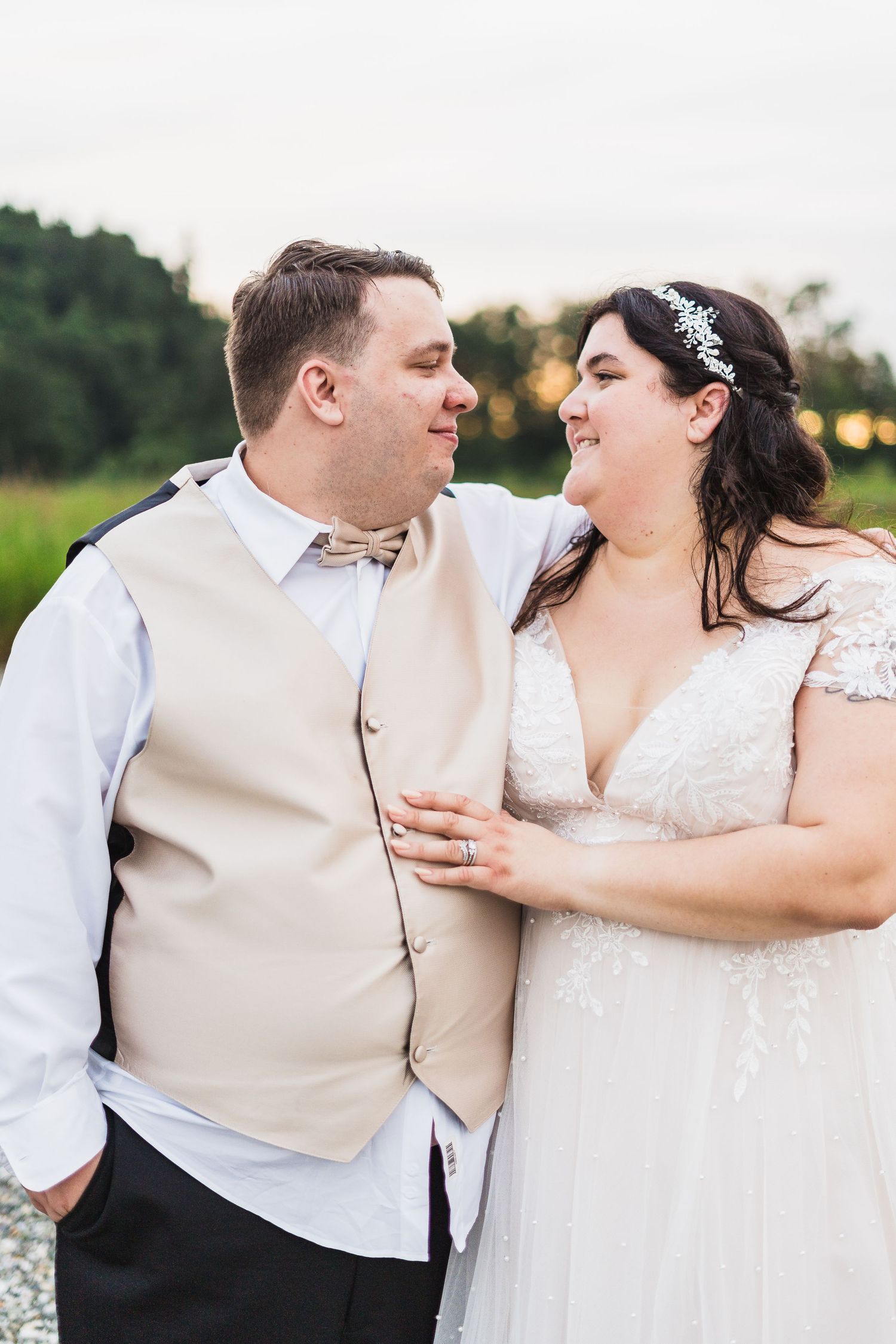 A happy couple shares a joyful moment together outdoors on their wedding day, wearing formal attire and smiling at each other.