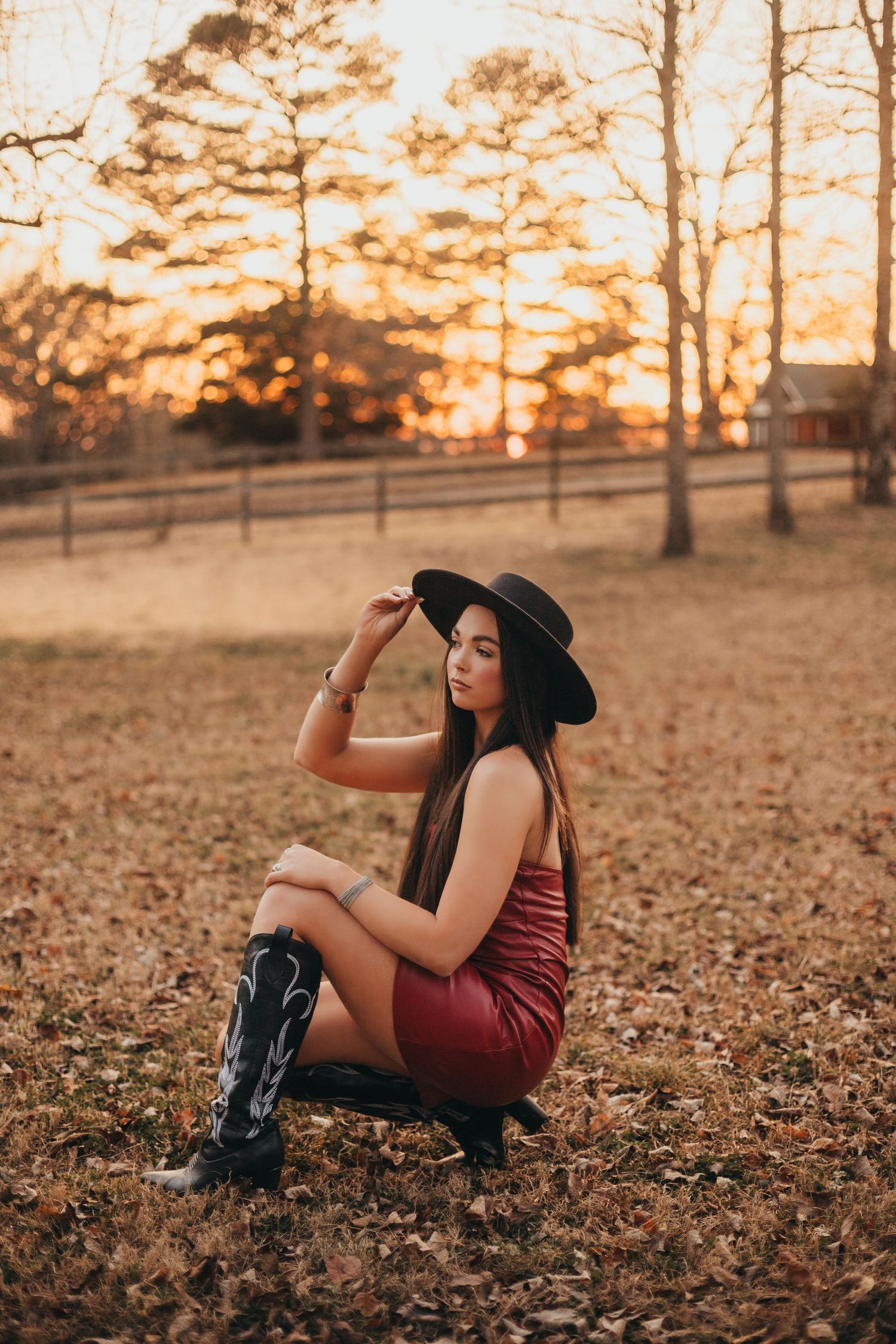 Autumn outdoor portrait session in fallen leaves during golden hour sunset among pine trees.