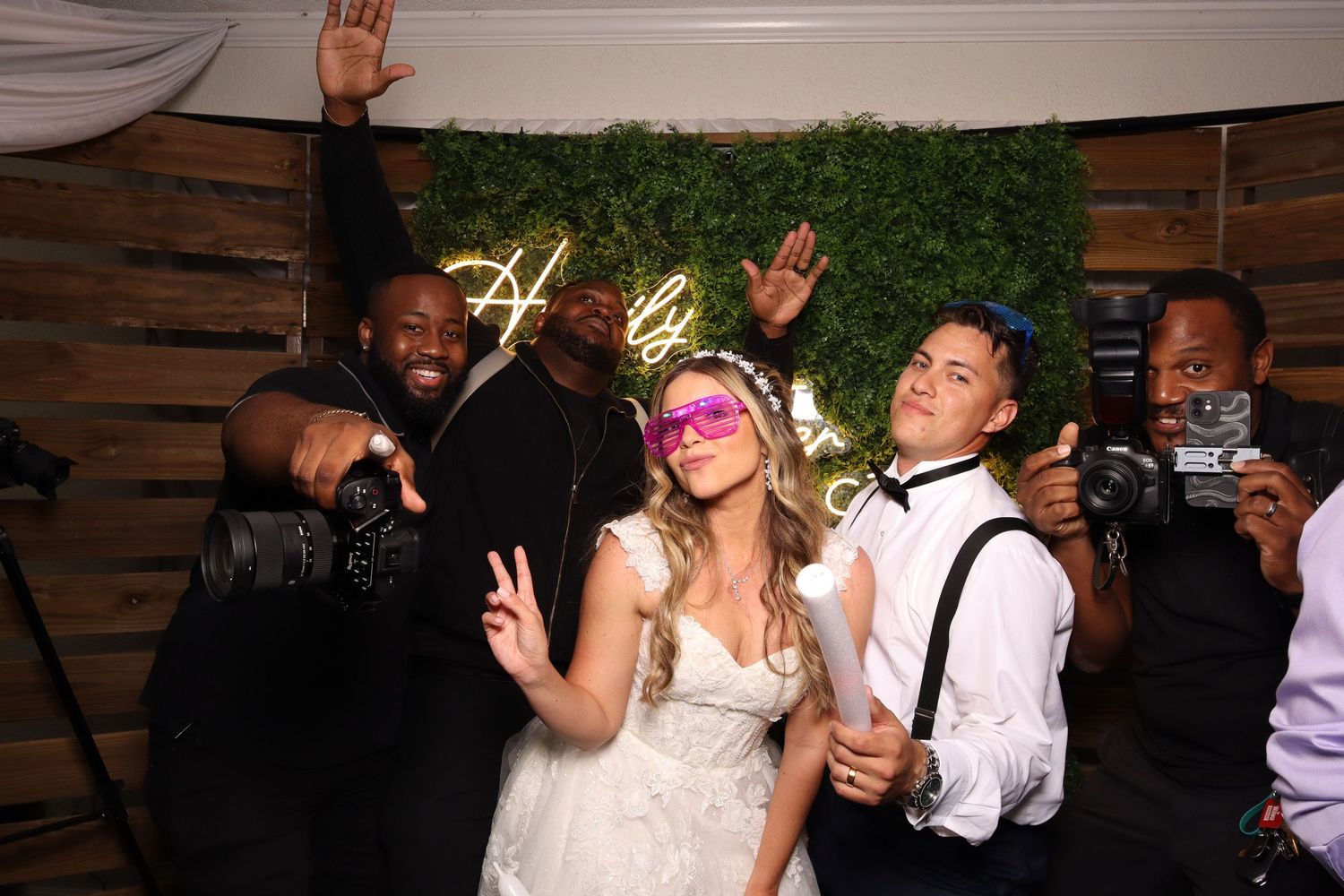 Wedding guests dance and celebrate together on a dimly lit dance floor during a lively reception party.