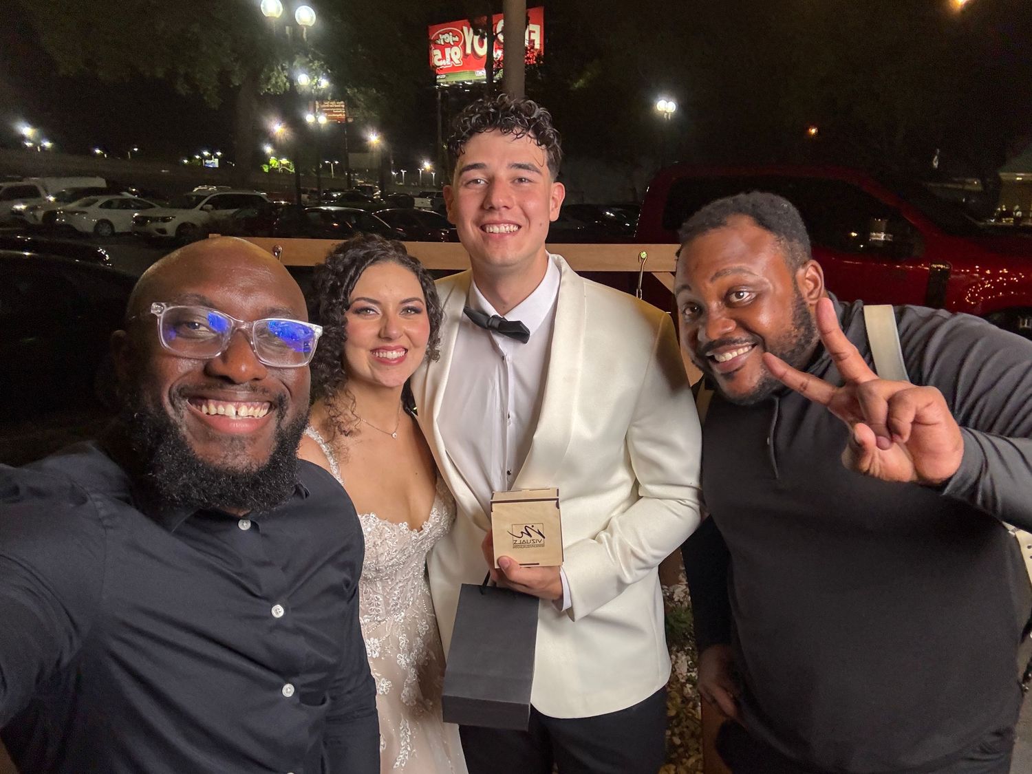 Group of friends smiling and posing together at a nighttime event.