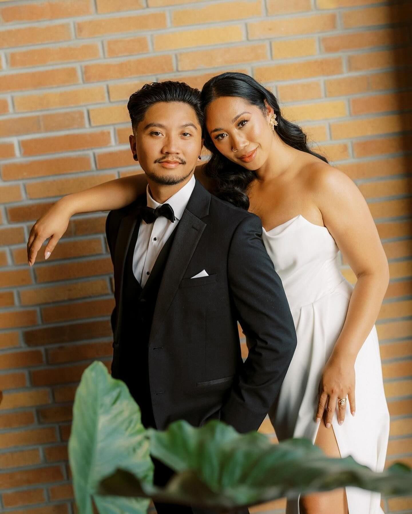 A bride and groom pose playfully against a brick wall in a series of wedding photos.