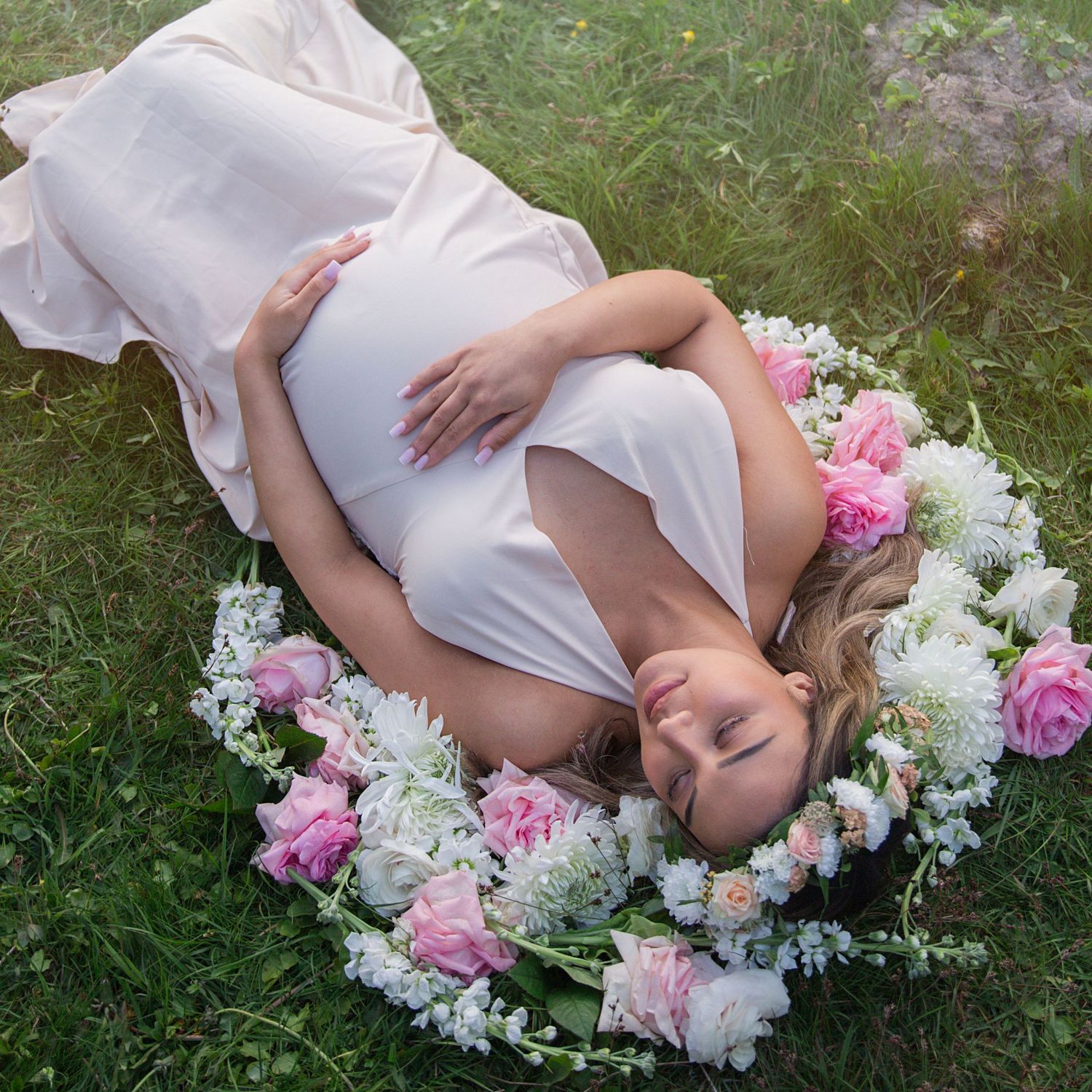 En blivande mamma i en lång klänning bland vilda blommor.