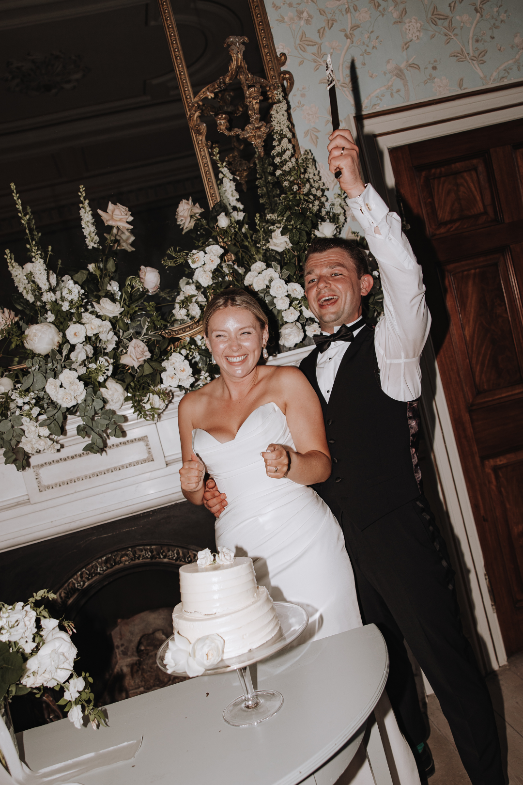 Newlywed couple cuts and feeds each other wedding cake during traditional cake cutting reception ceremony at Pynes House, Exeter.