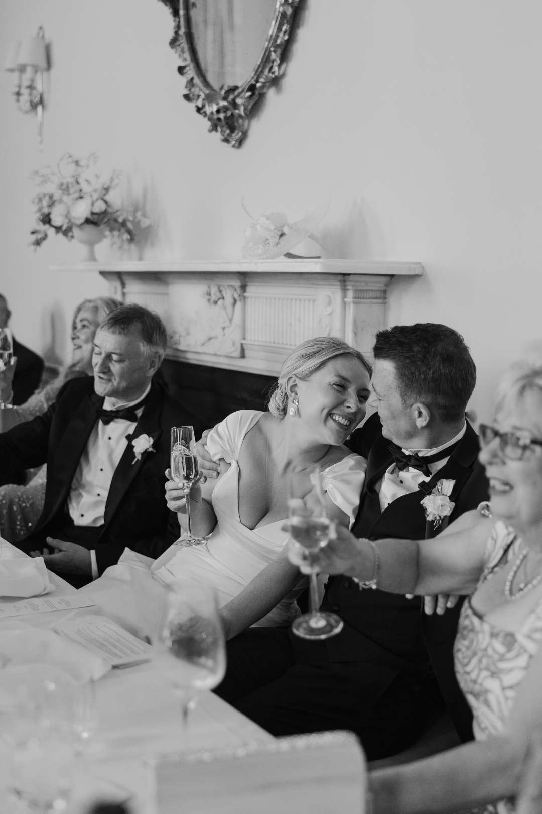 Reception guests laughing together while toasting at an elegant wedding celebration.