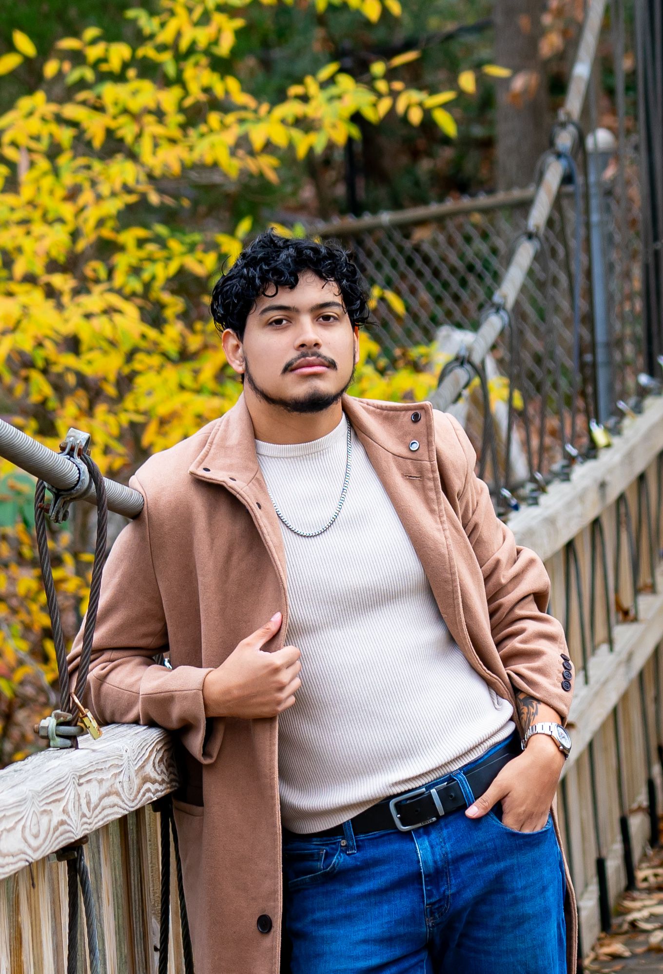 Fall fashion portrait against yellow foliage with wooden fence background.