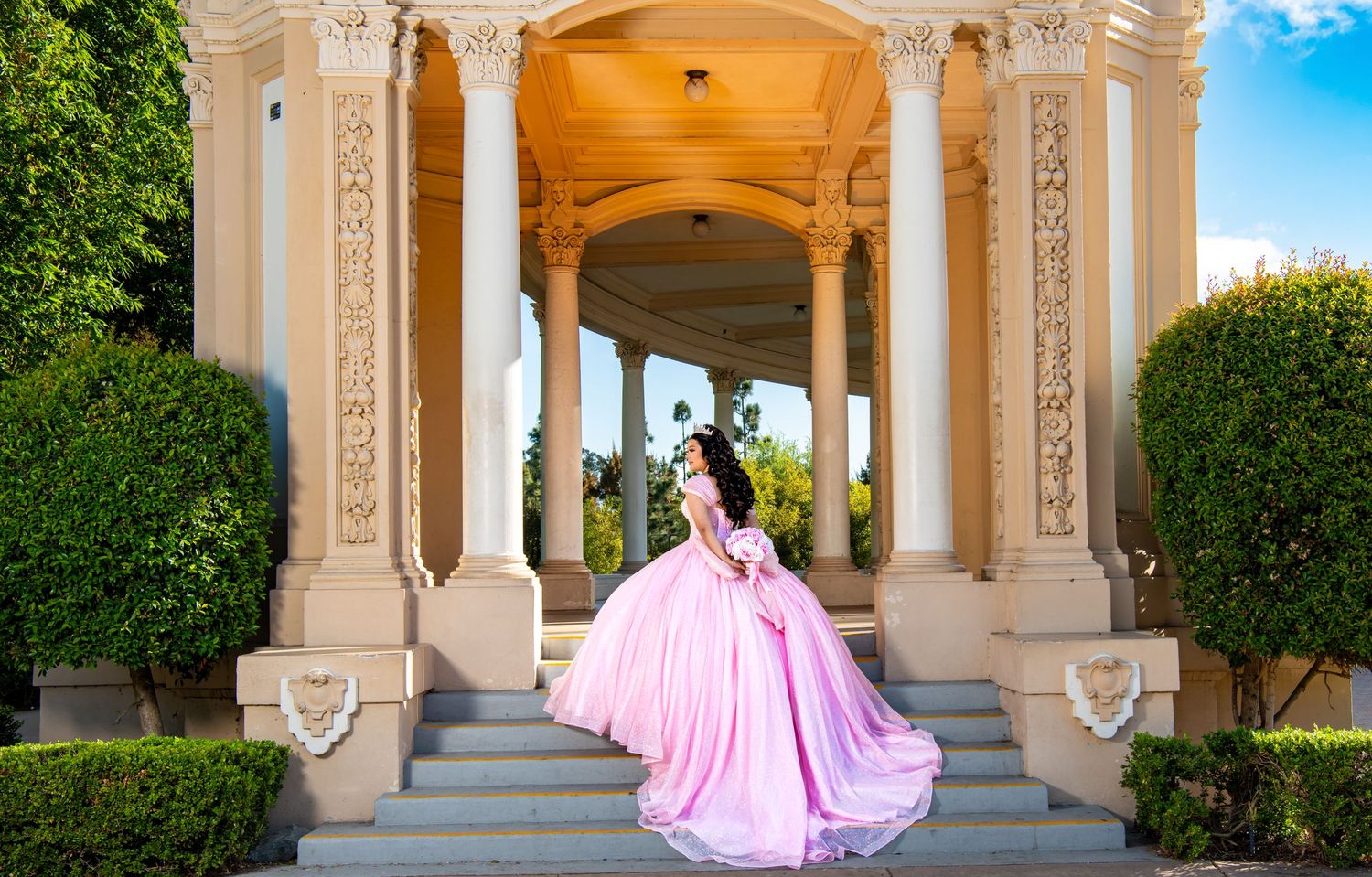 Architectural colonnade with pink gown flowing in outdoor wedding photoshoot.