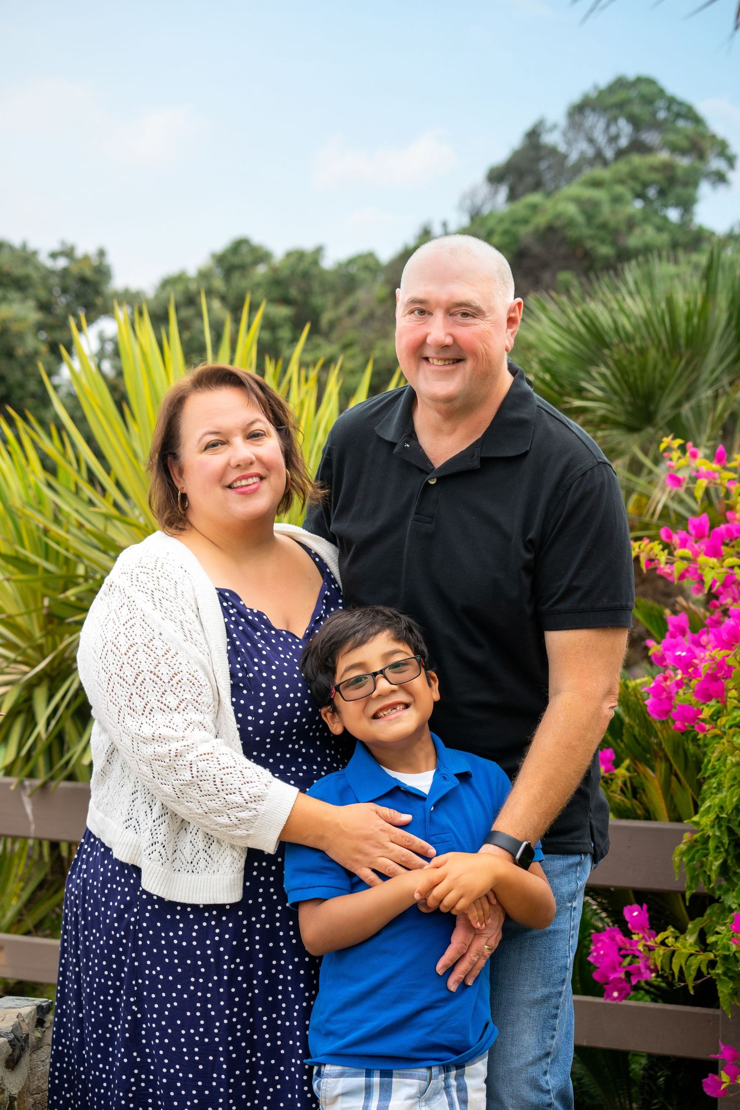 Colorful garden family portrait with tropical plants and bright pink flowers.