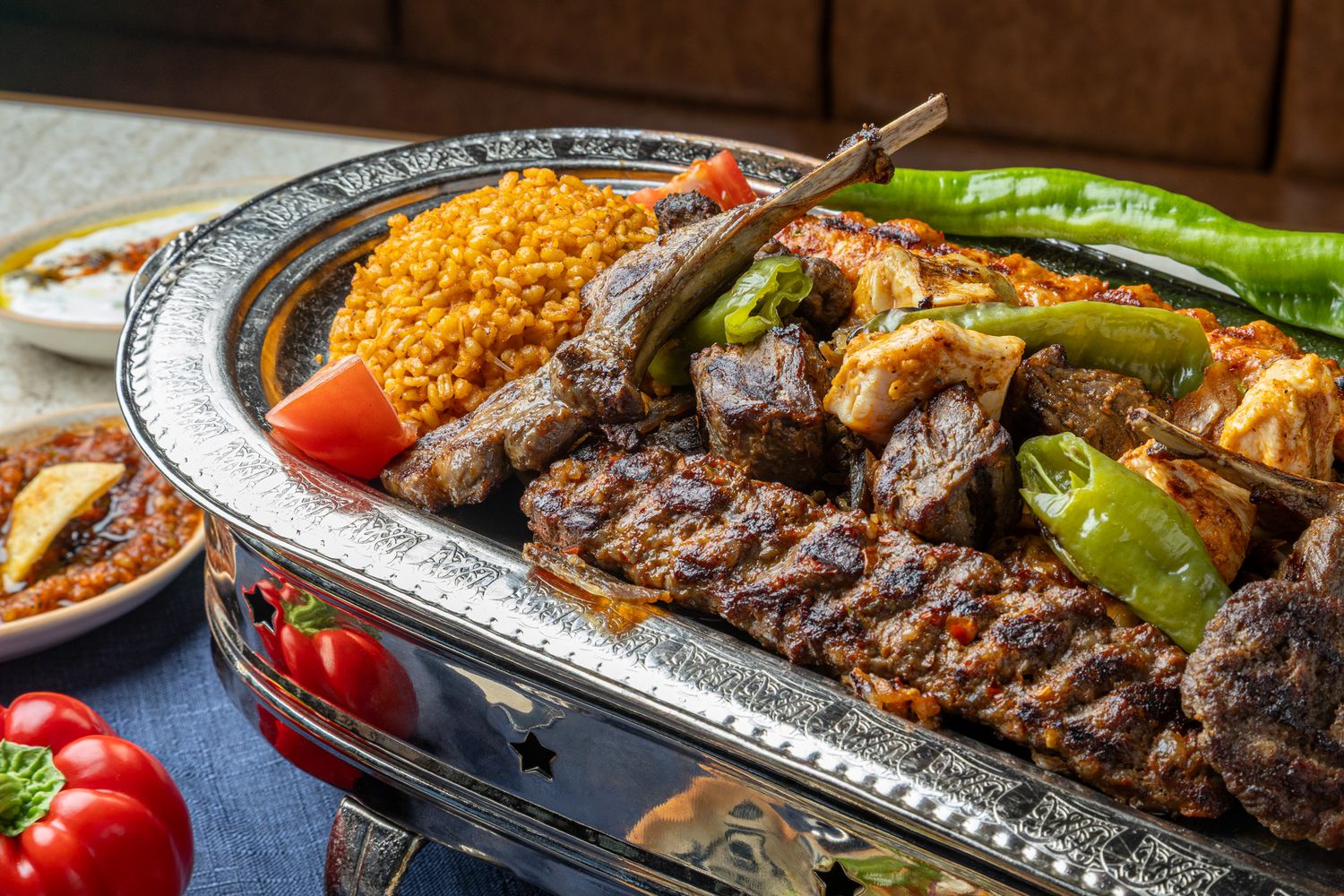 Restaurant photography of Turkish Grilled meat kebabs and vegetables served on ornate silver platters.