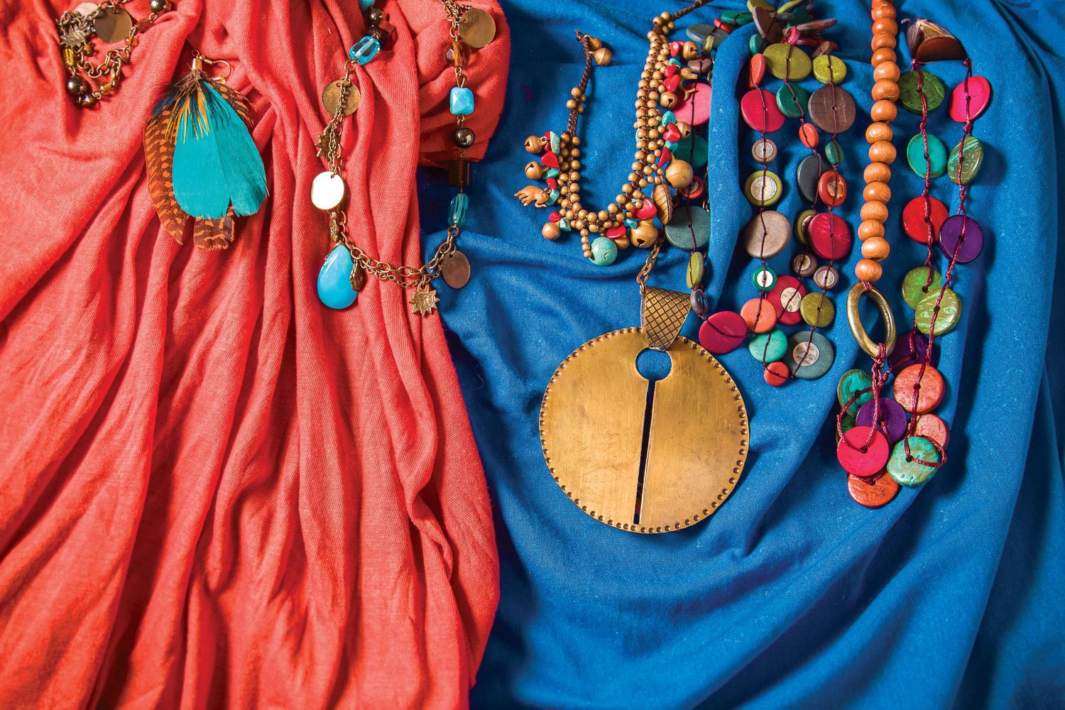 Colorful handmade beaded necklaces displayed against pink and blue fabric backdrop.
