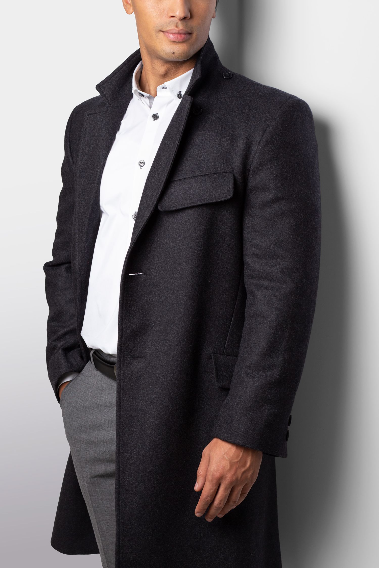 Professional portrait studio photo of someone wearing a black blazer jacket with white collar shirt against light background.