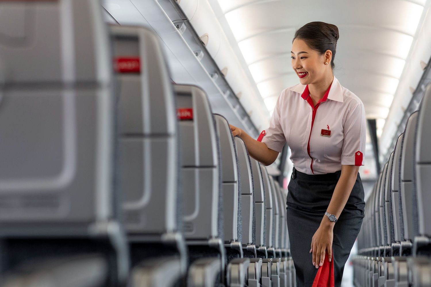 Flight attendant performing cabin check during boarding prep captured for branded airline photography and corporate video storytelling.