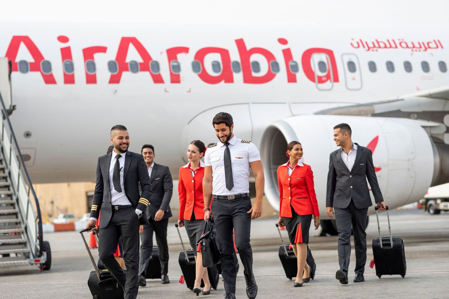 Air Arabia flight crew walking on tarmac with luggage – branded airline operations photography