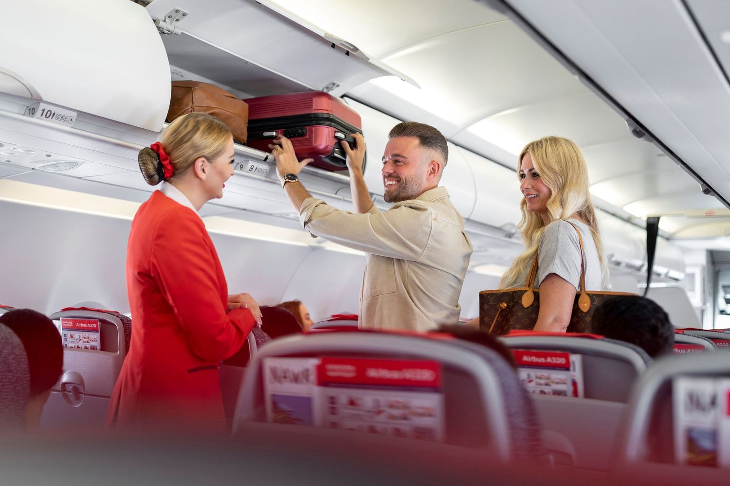 Passengers interact with flight attendants in the cabin of a commercial airplane during service.