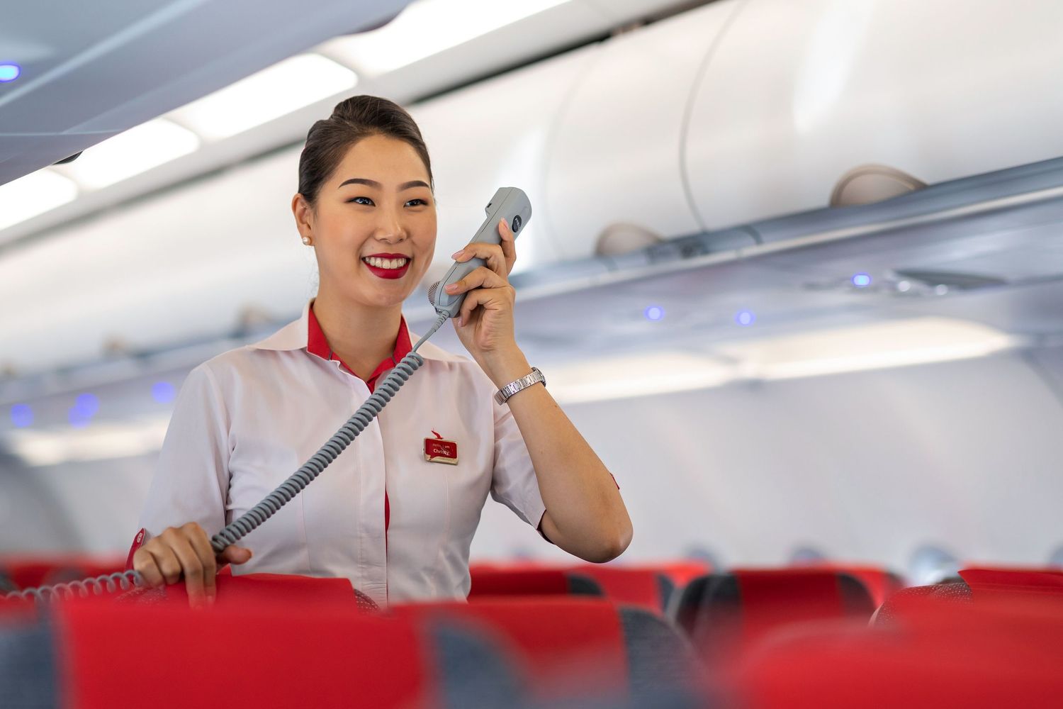 Flight attendant speaking through cabin intercom shot for branded airline marketing content.