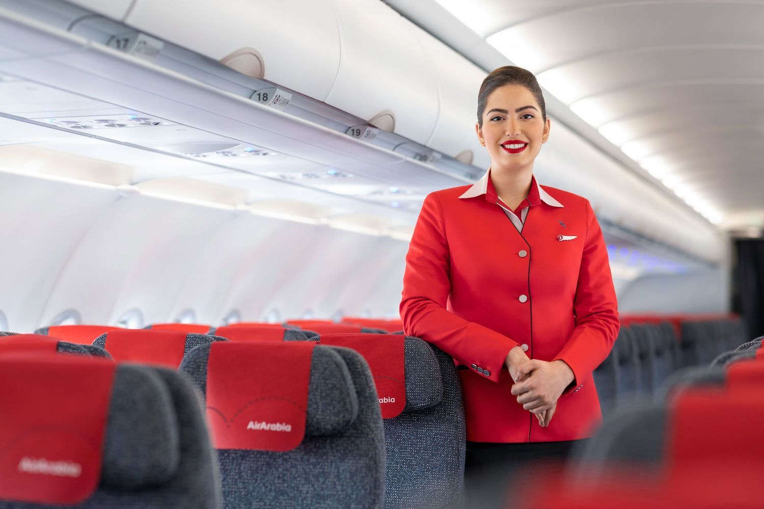 Flight attendant in red uniform standing for cabin crew portrait photography.