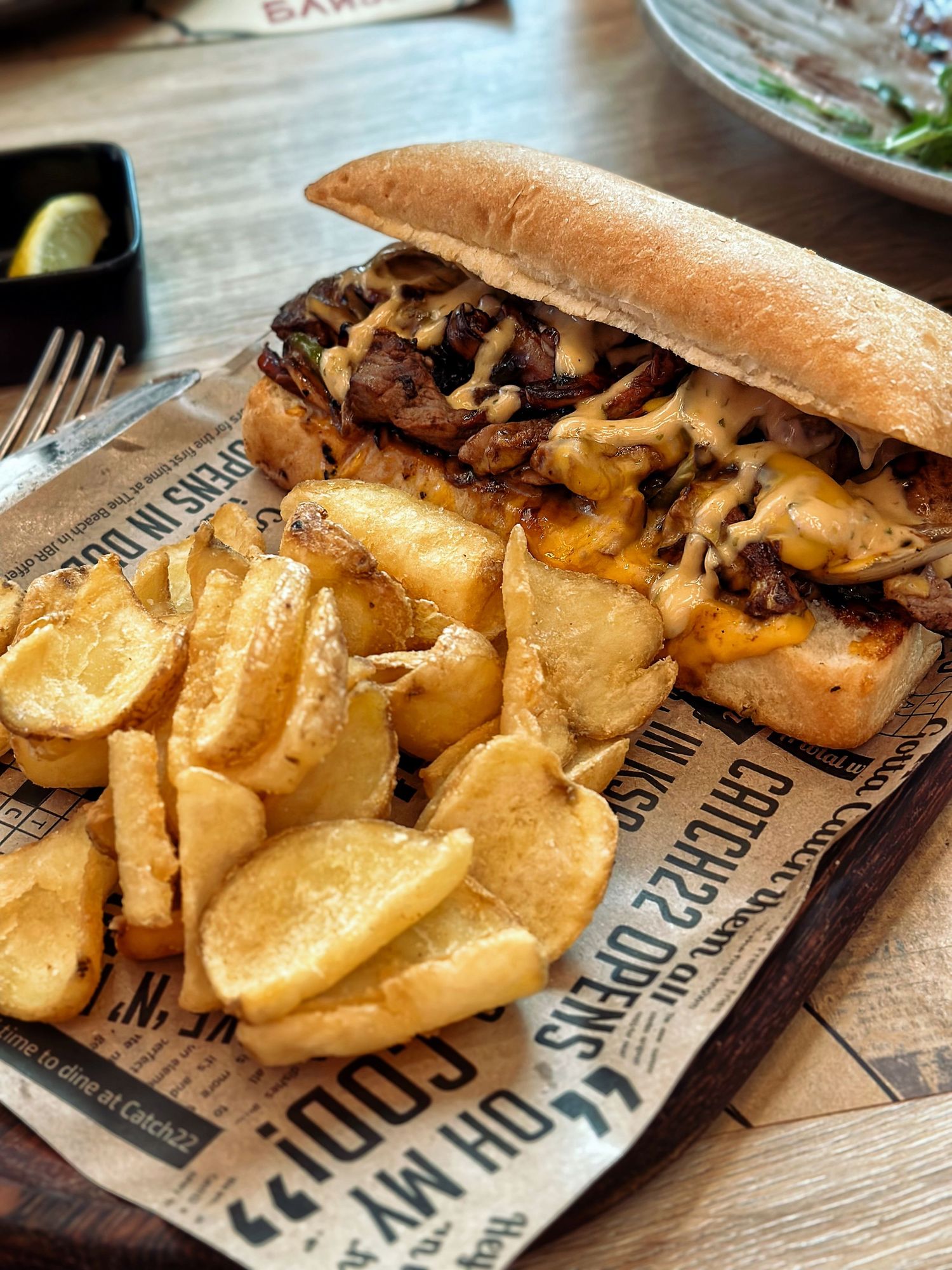 Classic Philly steak and cheese sandwich served with crispy fries, captured in a vibrant, casual food photography style for commercial promo