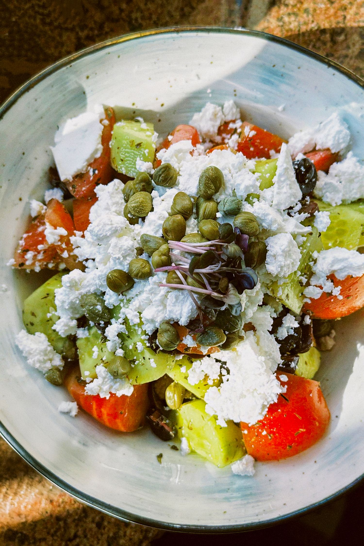 Greek salad photography with feta, tomato, cucumber, and caper mix, styled for creative social content.