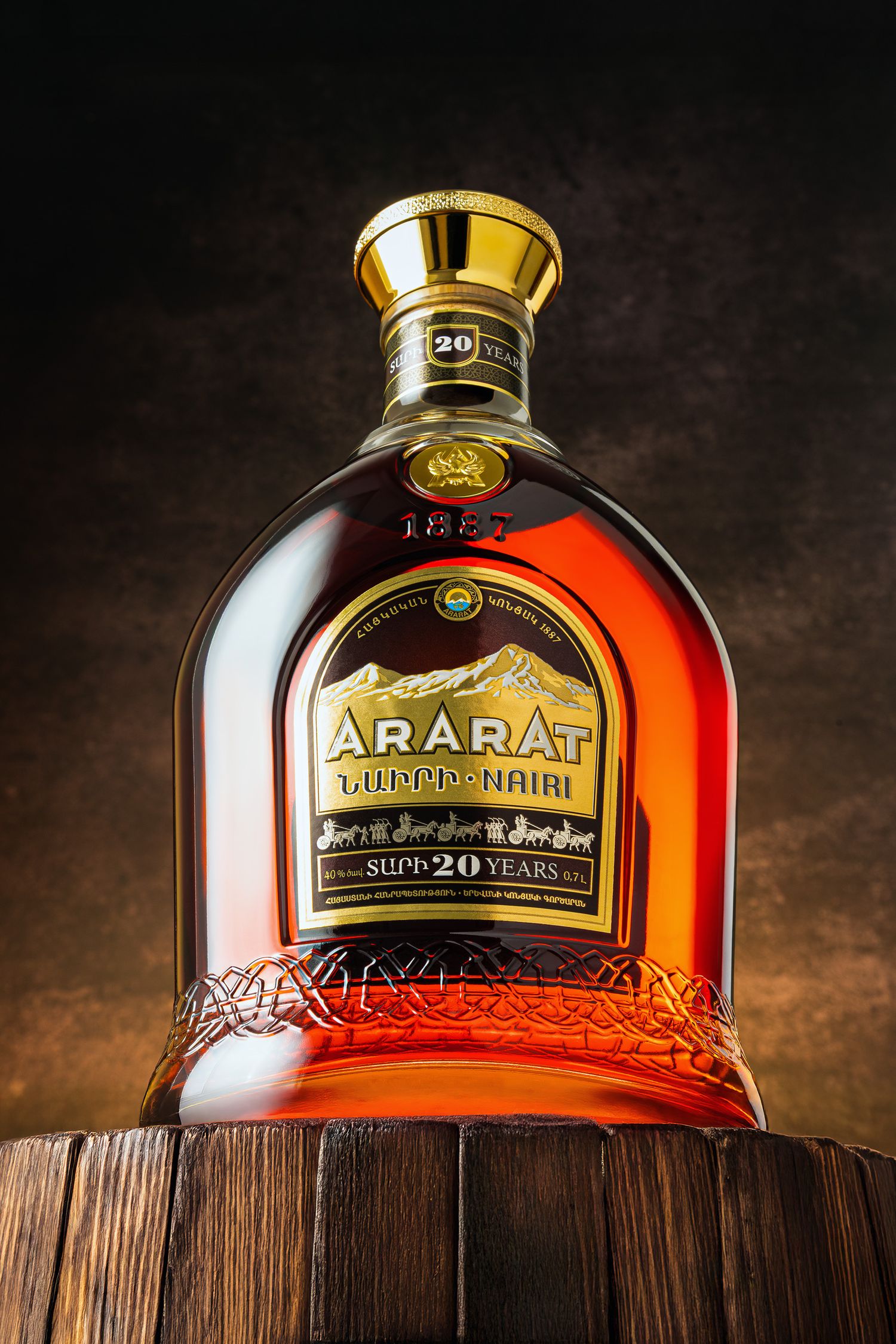 Close-up of Ararat aged brandy bottles displayed on wooden barrel headers showcasing their amber-colored liquid in ornate glass.