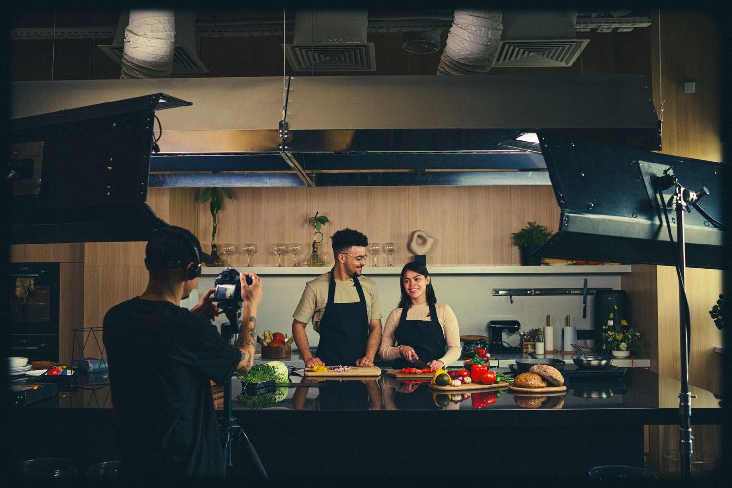 Professional chefs prepare dishes in a modern restaurant kitchen with stainless steel equipment and bright lighting.