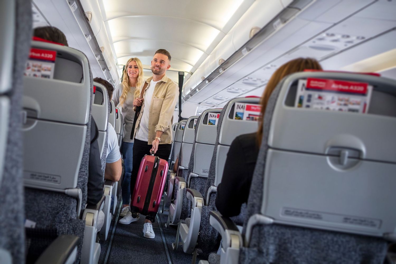 Aircraft cabin interior with red and gray seating, captured for branded airline photography and corporate video.