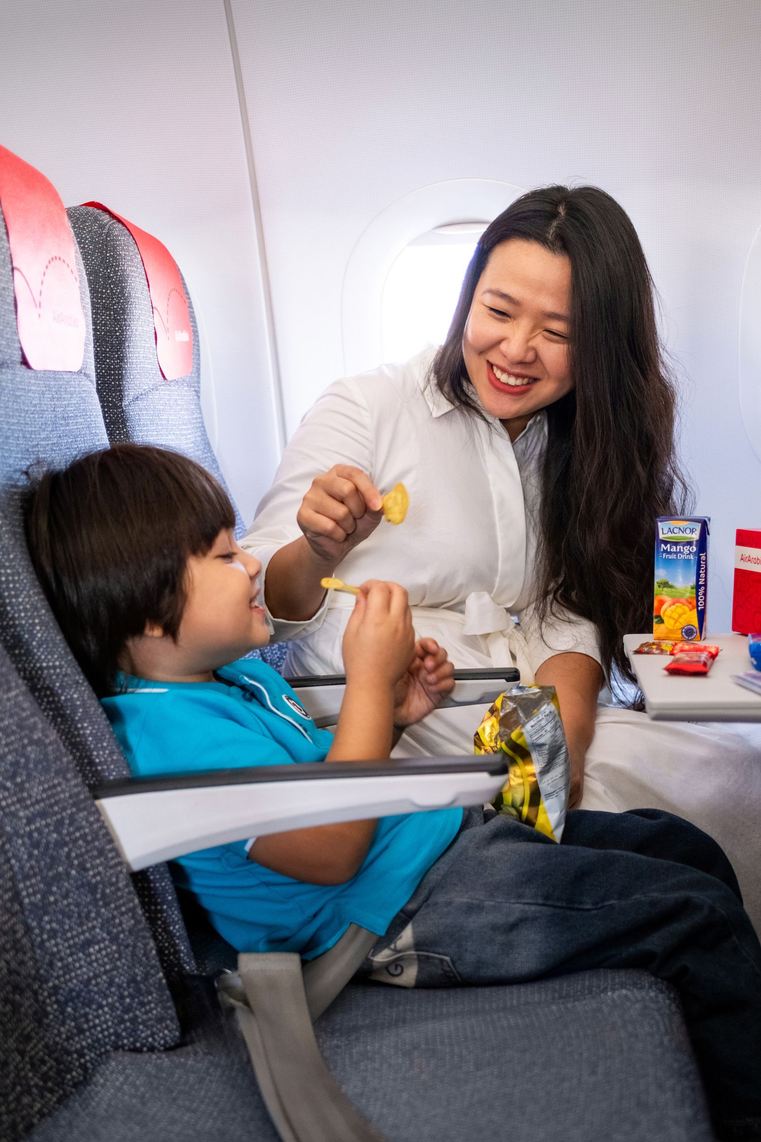Mother and child sharing snack during flight captured for family airline passenger experience photography