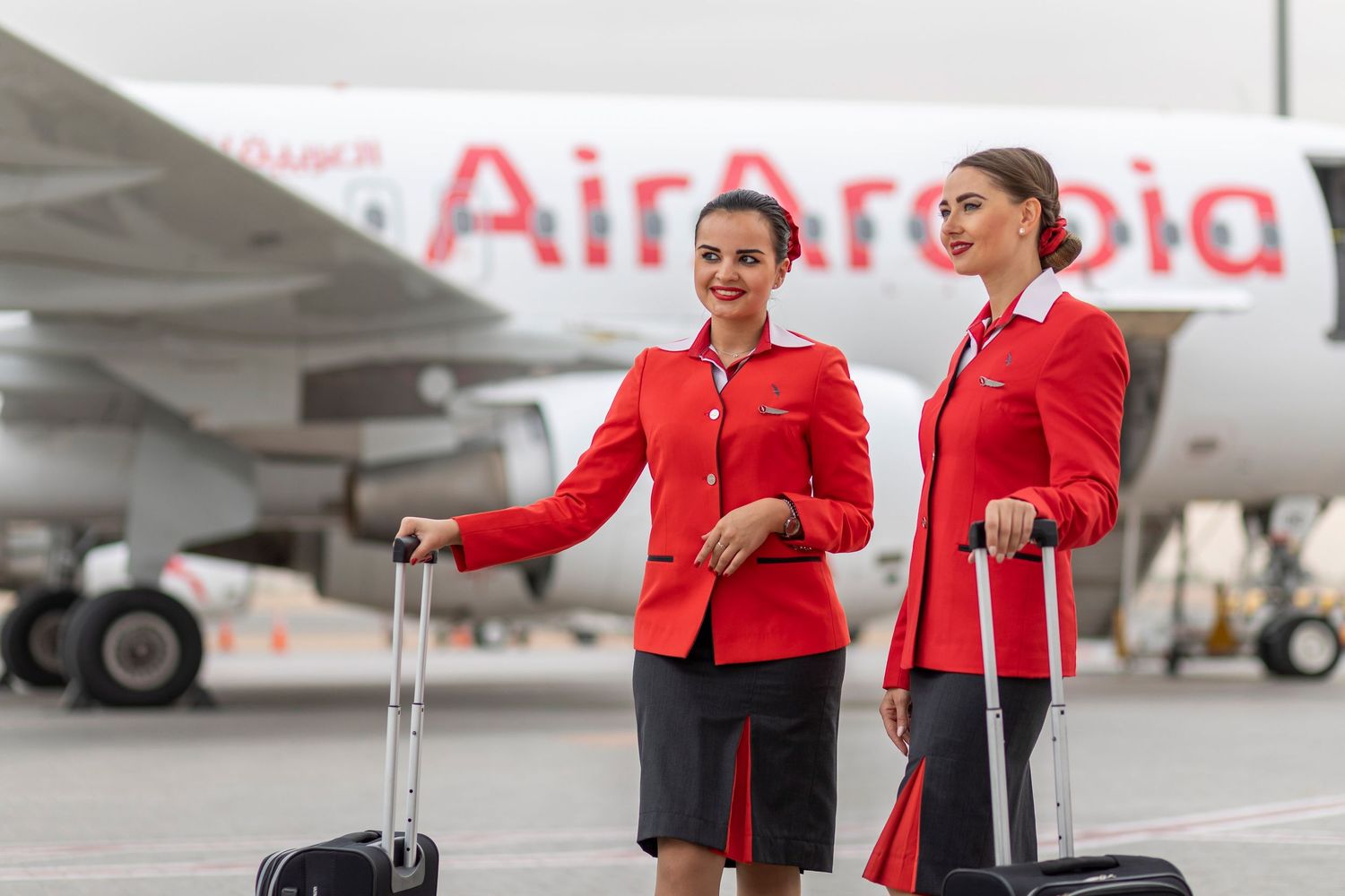 Airline ground crew in red uniforms preparing for departure near aircraft photographed for branded airline marketing content.